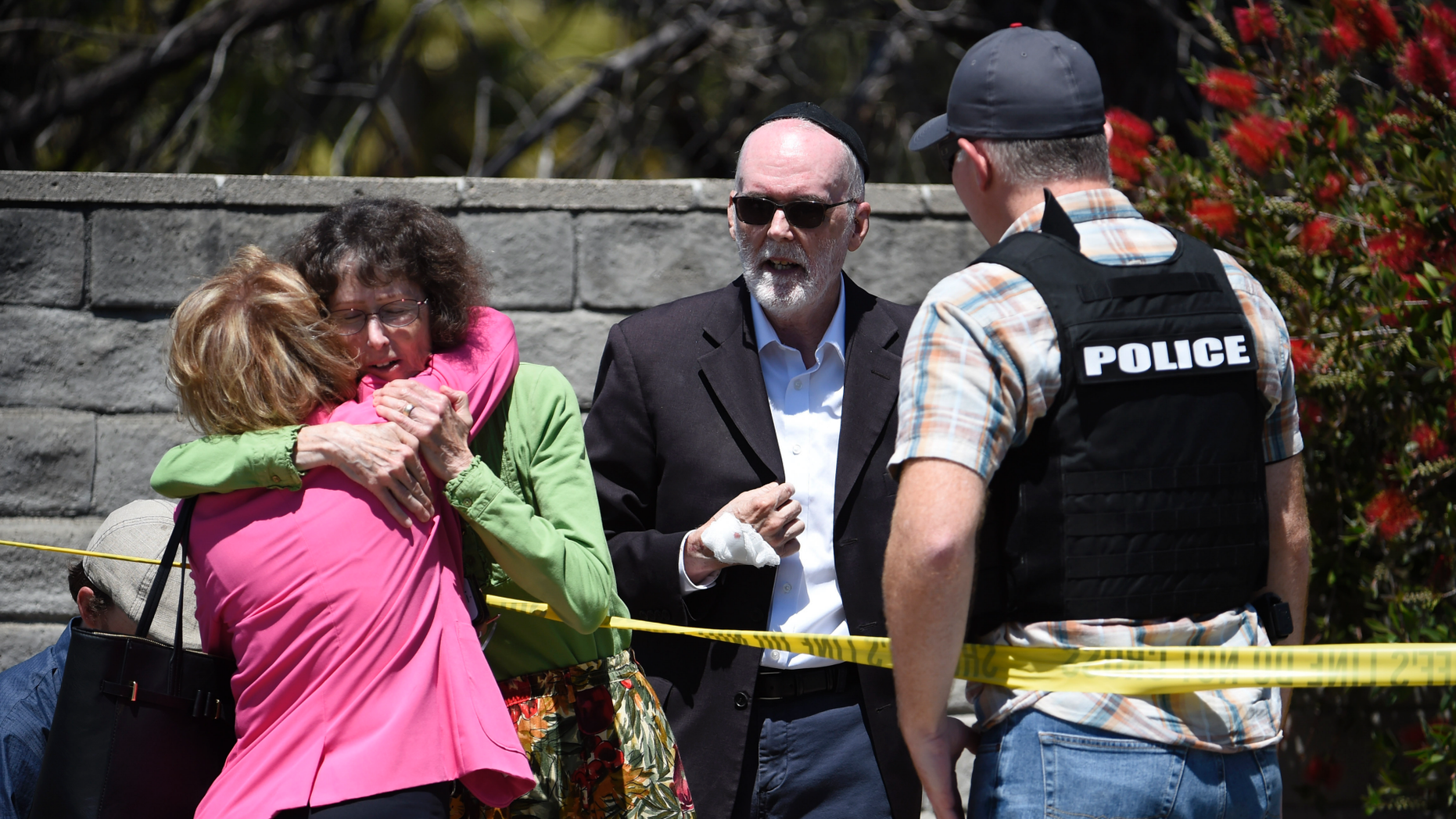 Two people kiss each other during a conversation with a representative of the San Diego County Sheriff in front of the Chabad of Poway Synagogue on Saturday, April 27, 2019 in Poway, California. A man opened fire in the interior of the synagogue near San Diego, while the faithful were celebrating the last of a great Jewish holiday. (AP Photo / Denis Poroy)
