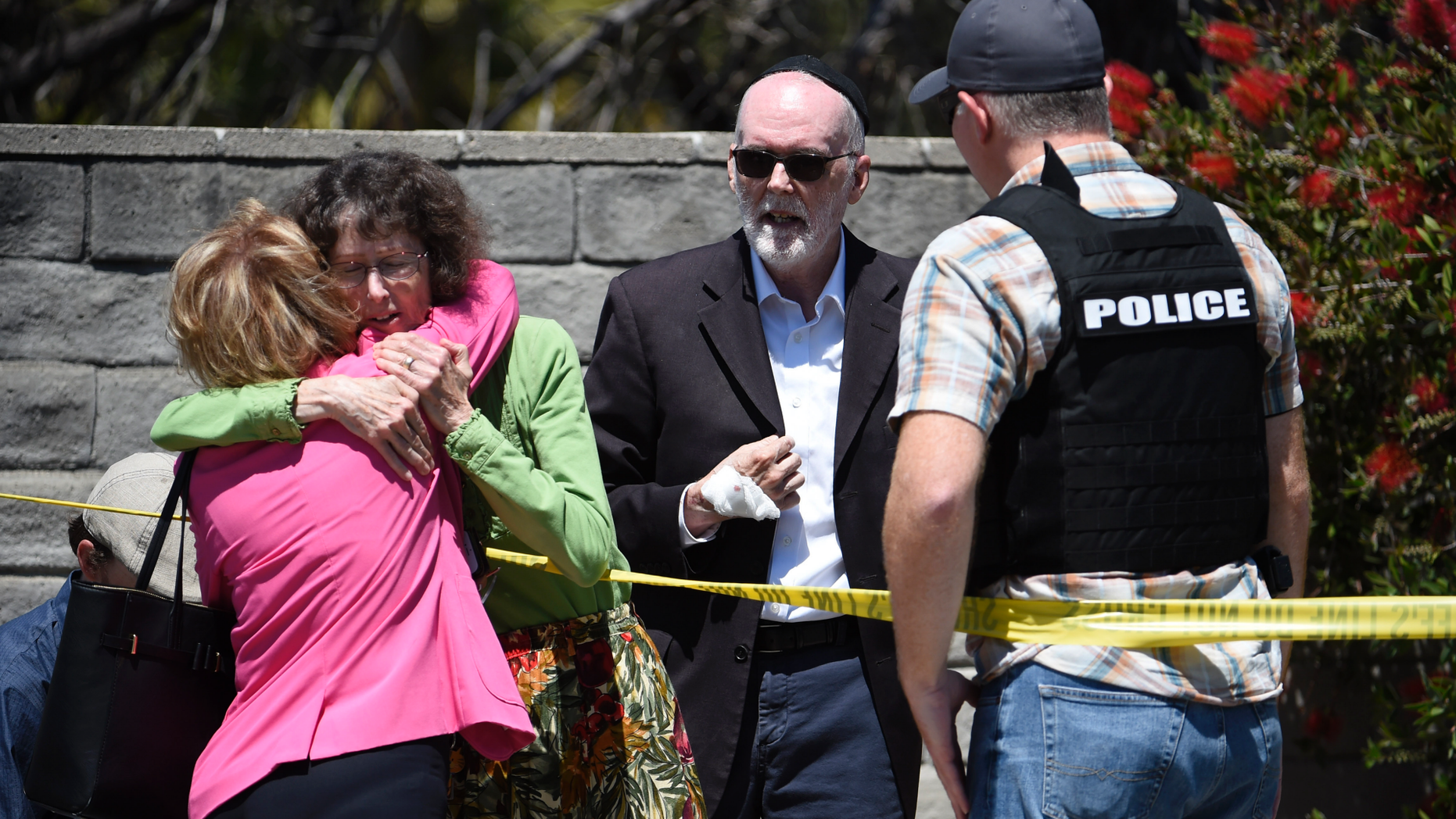 Two people hug as another talks to a San Diego County Sheriff's deputy outside of the Chabad of Poway synagogue, Saturday, April 27, 2019, in Poway, Calif. A man opened fire inside the synagogue near San Diego as worshippers celebrated the last day of a major Jewish holiday. (AP Photo/Denis Poroy)