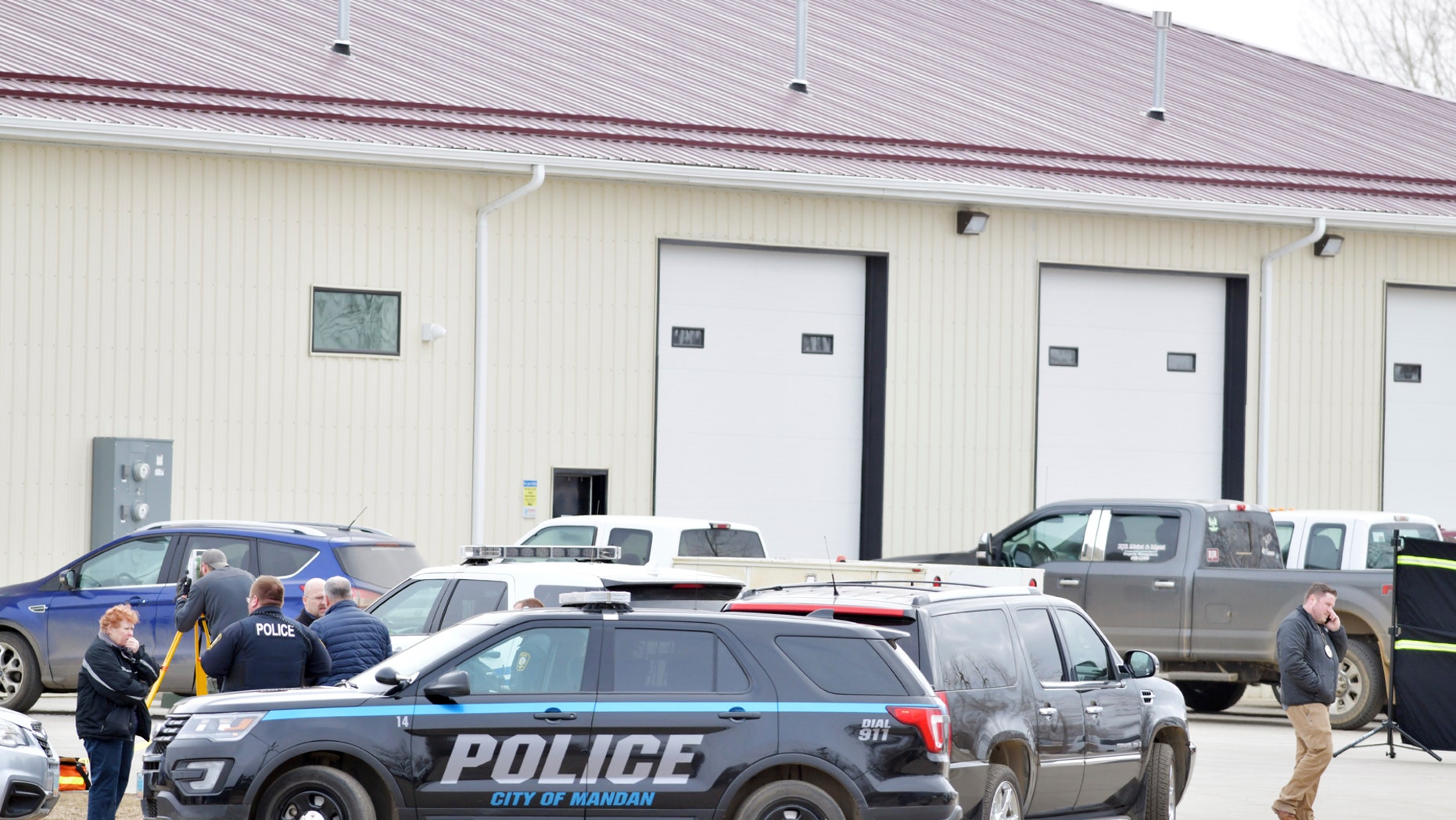 Mandan, ND Deputy Police Chief Lori Flaten, left, and other law enforcement officers standing in front of the scene on the south side of the RJR Maintenance and Management property in Mandan, ND, on Monday 1 April 1, 2019. (Mike McCleary / The Bismarck Tribune via AP)