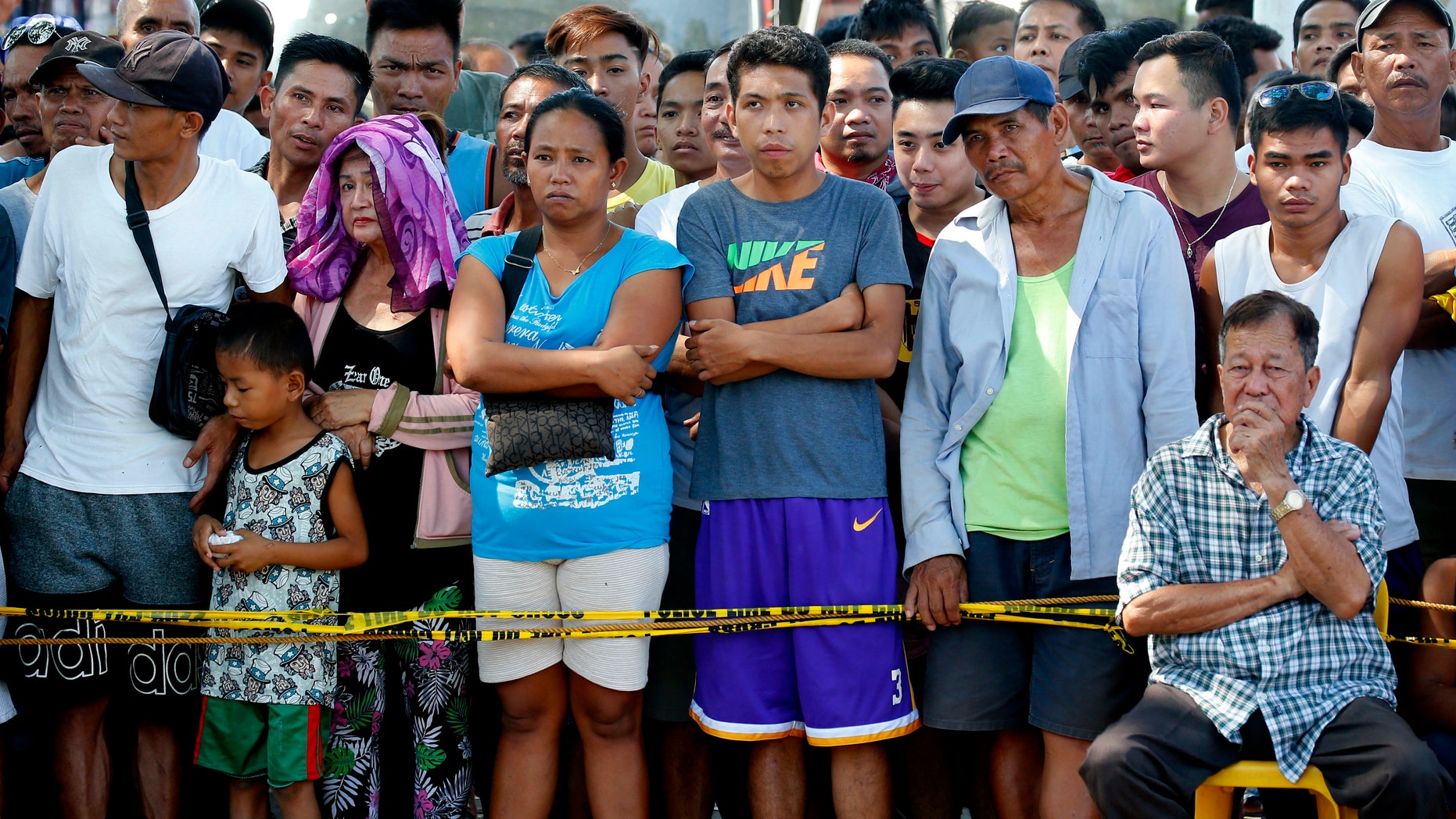 Residents watch as rescuers continue to search for survivors following Monday's 6.1 magnitude earthquake that caused the collapse of a commercial building in Porac township, Pampanga province, north of Manila.