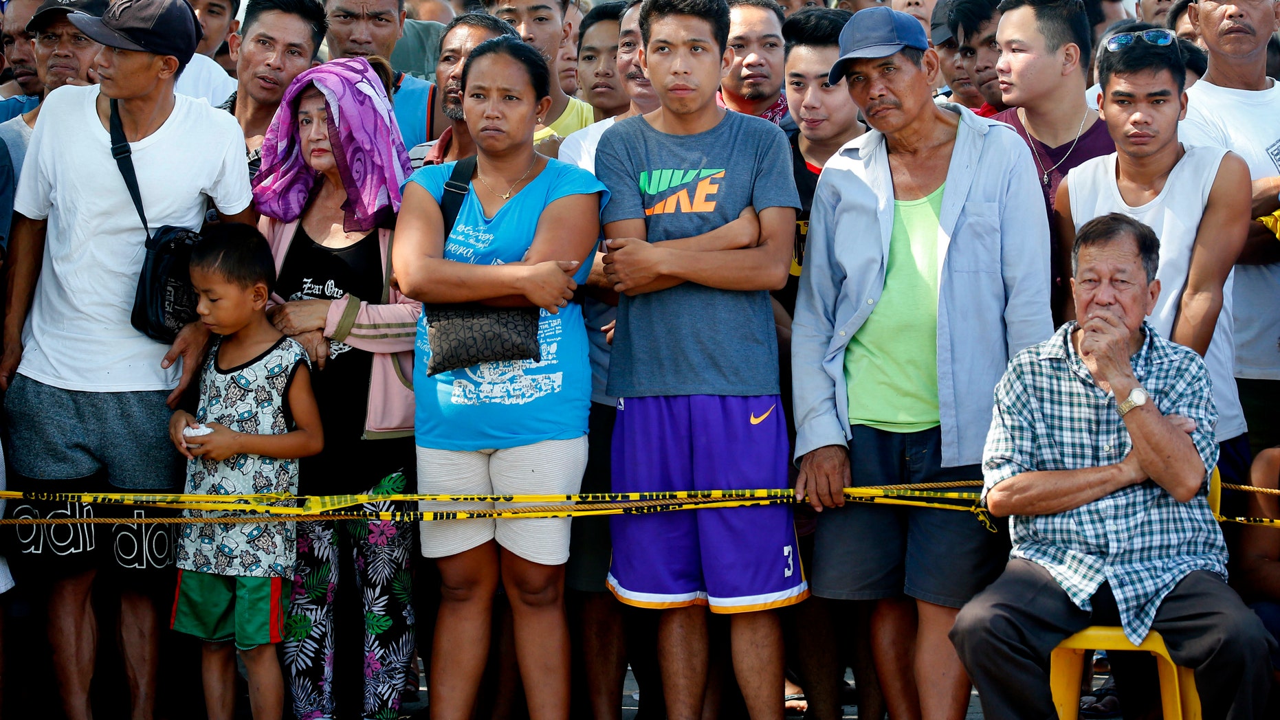 Residents watch as rescuers continue to search for survivors following Monday's 6.1 magnitude earthquake that caused the collapse of a commercial building in Porac township, Pampanga province, north of Manila.