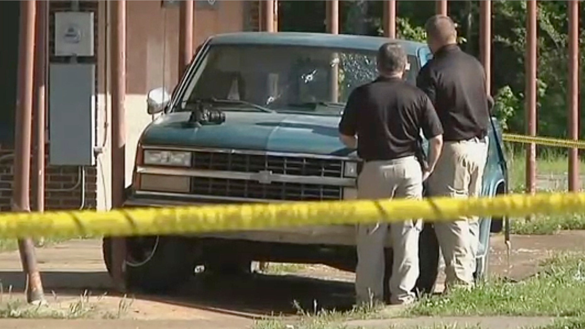 In this Friday, April 26, 2019 image made from video provided by KTEN, investigators inspect a pickup truck with bullet holes in its windshield in Hugo, Okla. Olivia Hill says Oklahoma police fired at William Devaughn Smith in the vehicle with her and her four children, with two of her kids suffering head wounds and another shot in the face.