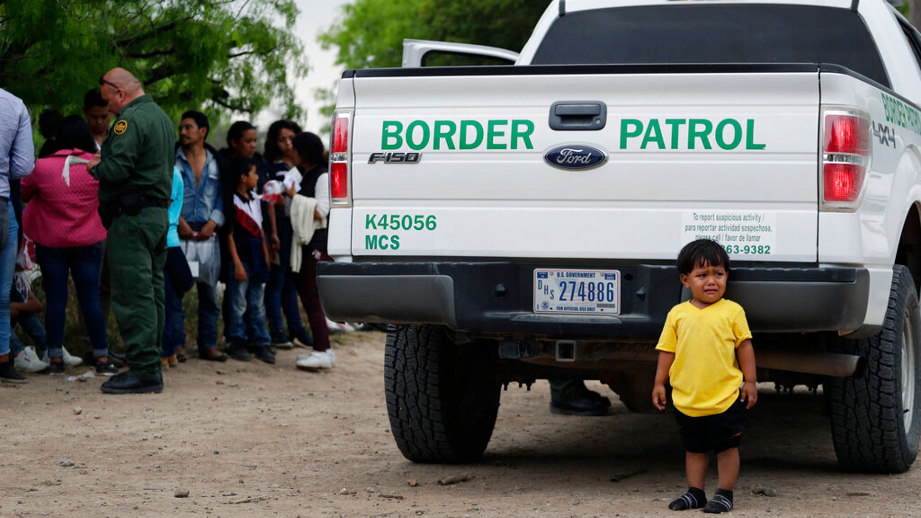 In this Thursday, March 14, 2019, photo, William Josue Gonzales Garcia, 2, who was traveling with his parents, waits with other families who crossed the nearby U.S.-Mexico border near McAllen, Texas. They are waiting for Border Patrol agents to check names and documents. Immigration authorities say they expect the ongoing surge of Central American families crossing the border to multiply in the coming months. (AP Photo/Eric Gay)