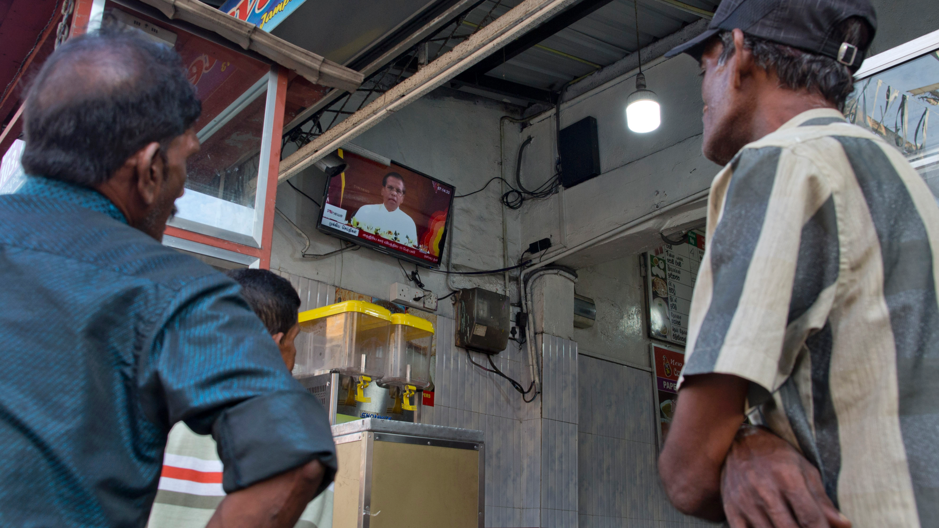 People gather around a television in a cafe showing Sri Lankan President Maithripala Sirisena's address to the nation following Easter Sunday terror attacks in Colombo, Sri Lanka, Wednesday, April 24, 2019. (AP Photo/Gemunu Amarasinghe)