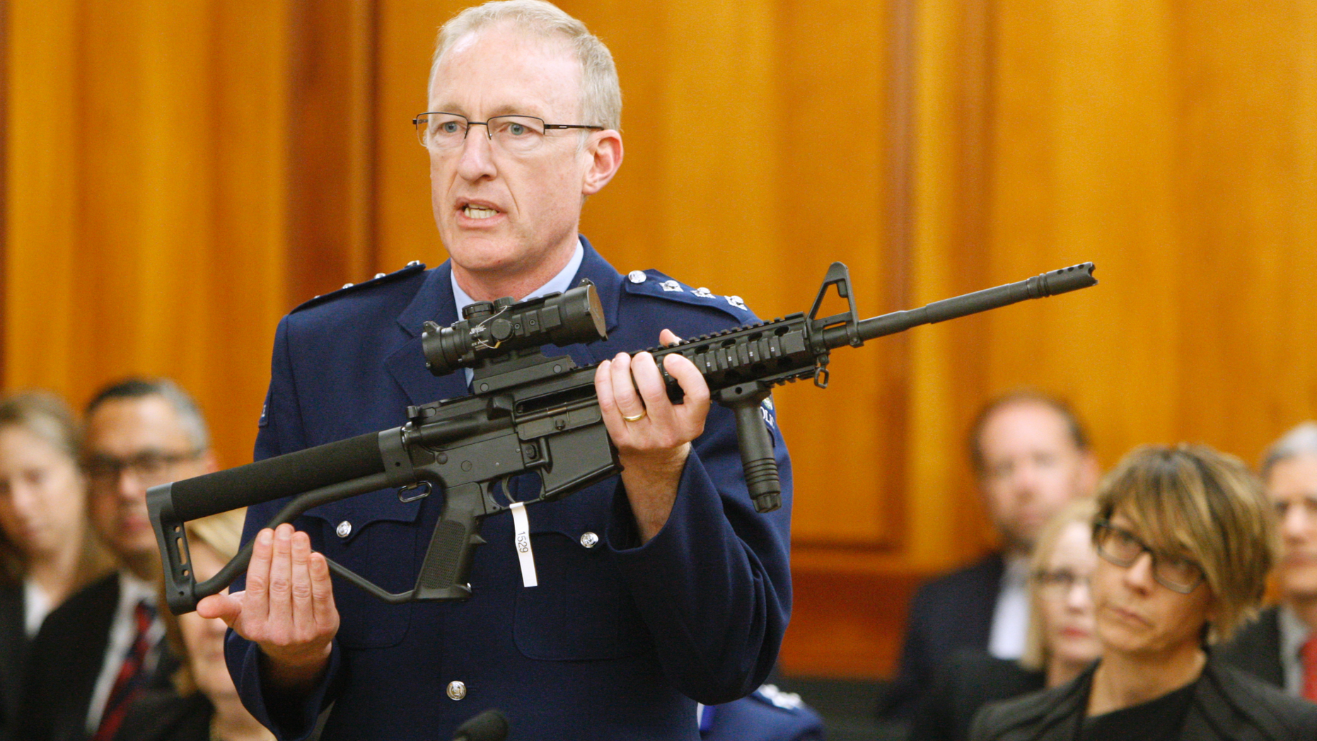 FILE - In this April 2, 2019, file photo, Police acting superintendent Mike McIlraith shows New Zealand lawmakers in Wellington, New Zealand, an AR-15 style rifle similar to one of the weapons a gunman used to slaughter 50 people at two mosques. New Zealand's new gun laws have been signed into law and now ban military-style weapons, just one day after the nation’s parliament overwhelmingly approved legislation to outlaw them less than a month after a man used such guns to kill 50 worshippers at two mosques. (AP Photo/Nick Perry, File)