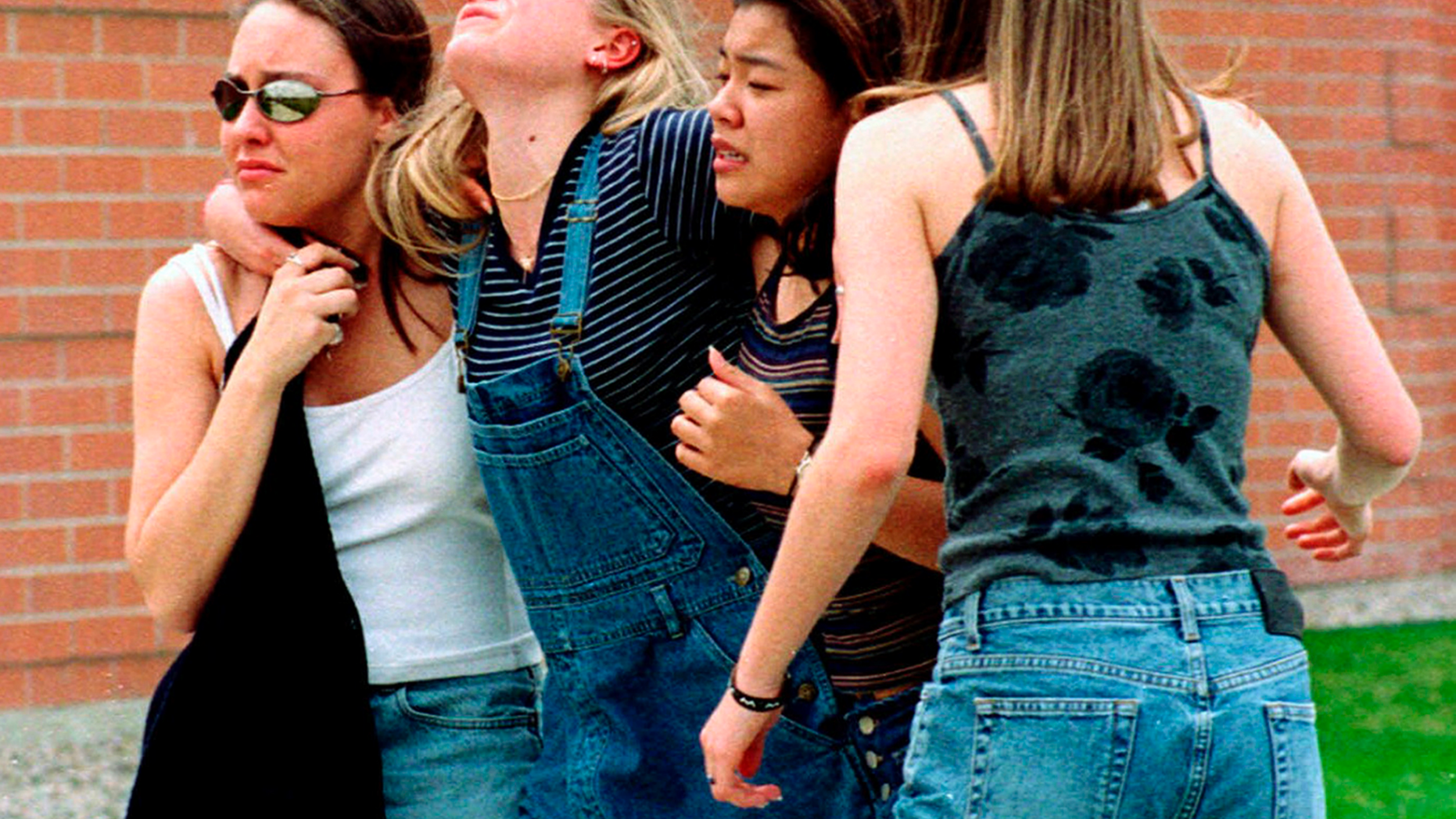 FILE - In this April 20, 1999, file photo, women head to a library near Columbine High School where students and faculty members were evacuated after two gunmen went on a shooting rampage in the school in the Denver suburb of Littleton, Colo. Twelve students and one teacher were killed in a murderous rampage at the school on April 20, 1999, by two students who killed themselves in the aftermath. (AP Photo/Kevin Higley, File)