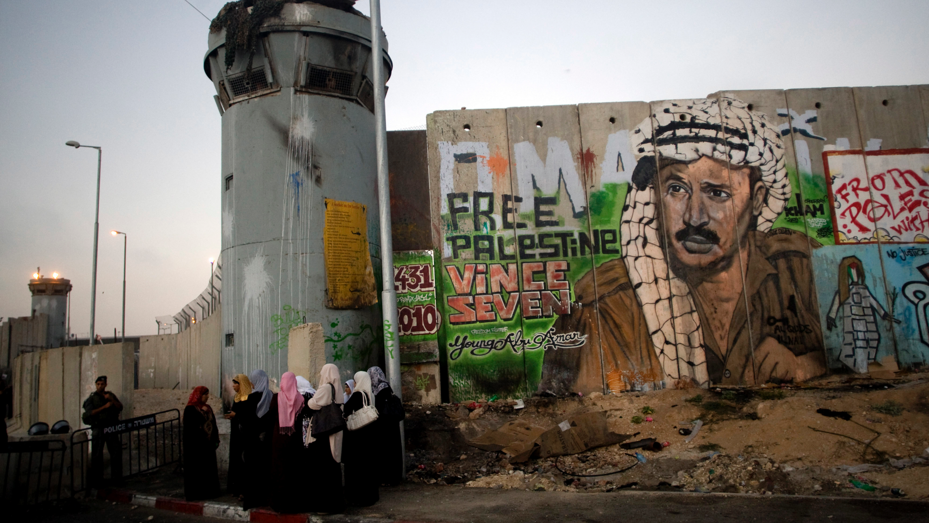 File - In this Friday, Aug. 13, 2010 file photo, Palestinian women wait near a section of Israel's separation barrier covered in graffiti, one depicting the late Palestinian leader Yasser Arafat, at the Qalandiya checkpoint , between Jerusalem and the West Bank city of Ramallah. Israel's election this month may have dimmed hopes for a two-state solution with the Palestinians as a way of resolving one of the Middle East's most intransigents conflicts. The vote, in which Prime Minister Benjamin Netanyahu coasted to another victory, left no doubt that peace talks with the Palestinians won't be on the agenda anytime soon. (AP Photo/Sebastian Scheiner, File)