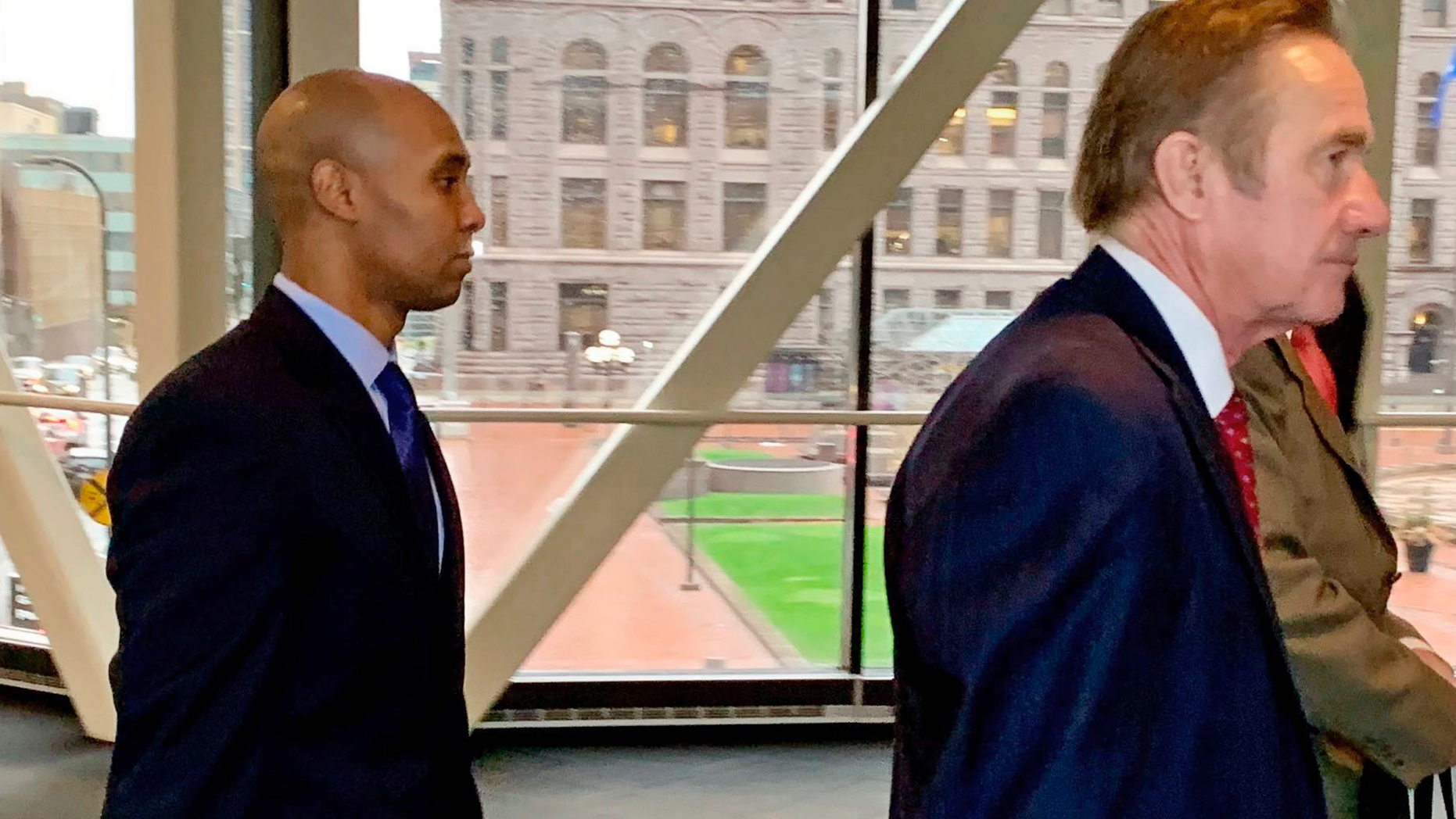 Former Minneapolis police officer Mohamed Noor, left, arrived with his defense attorneys Peter Wold, center, and Thomas Plunkett, right, partially hidden, on April 17, 2019, before another day of testimony in Noor's murder and manslaughter trial in Minneapolis. Noor is accused of fatally shooting an unarmed woman, Justine Ruszczyk Damond, on July 15, 2017, after she called 911 to report a possible sexual assault near her home. (AP Photo/Jeff Baenen)