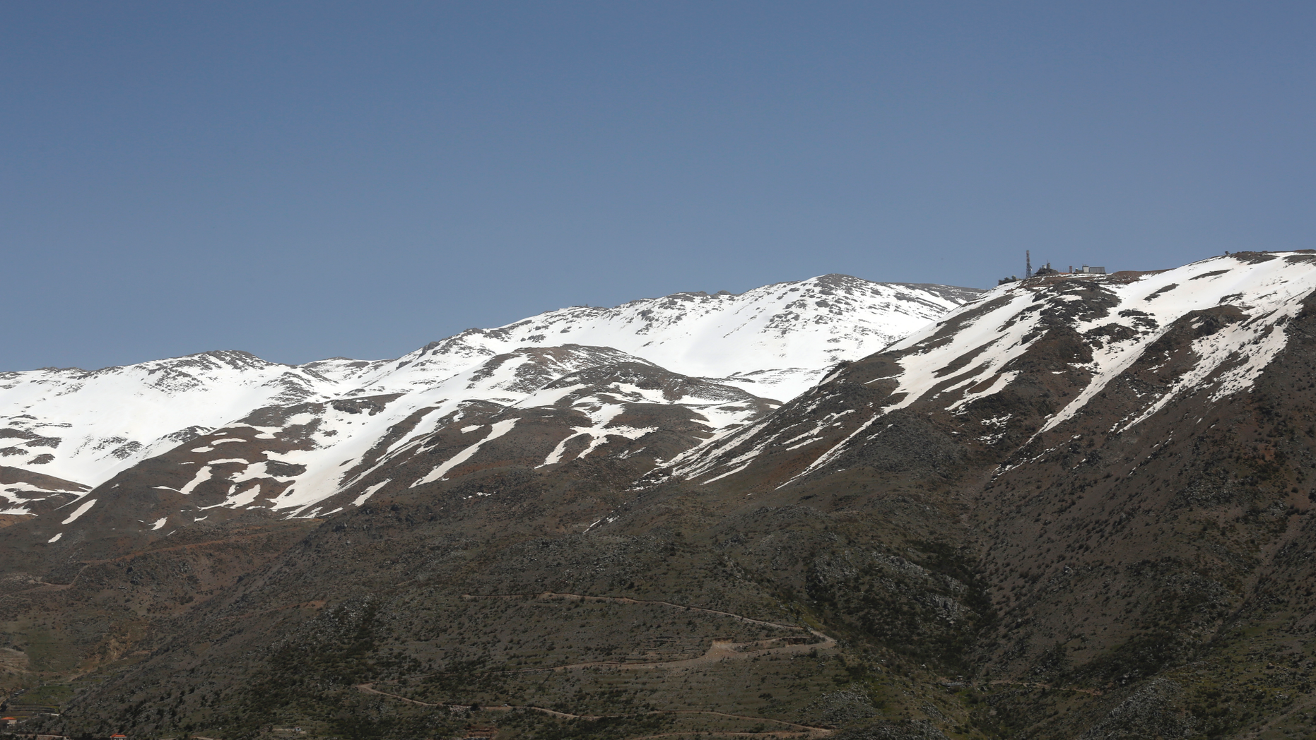 In this Tuesday, April 9, 2019 photo, an Israeli military position, right, is seen on the top of Mount Hermon in the Israeli-controlled Golan Heights, where the borders between Israel, Syria and Lebanon meet. U.S. President Donald Trump's move to recognize Israel's sovereignty over the occupied Golan Heights has caused concern in Lebanon over its claim to the disputed Chebaa Farms and adjacent Kfar Chouba hills, which Israel occupied alongside the Golan in 1967.(AP Photo/Hussein Malla)