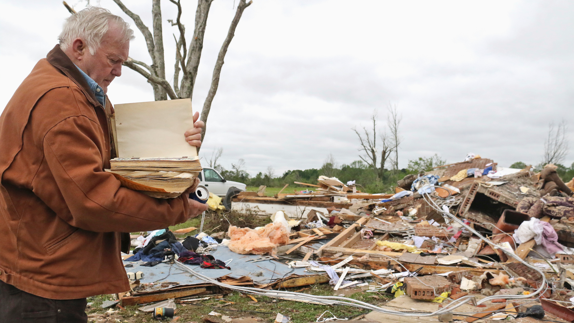 Robert Scott examines a family Bible that he just came out of the rubble on Sunday, April 14, 2019, from his home at Seely Drive, outside of Hamilton, Missouri, after An apparent tornado hit Saturday night, April 13, 2019. (AP Photo / Jim Lytle)