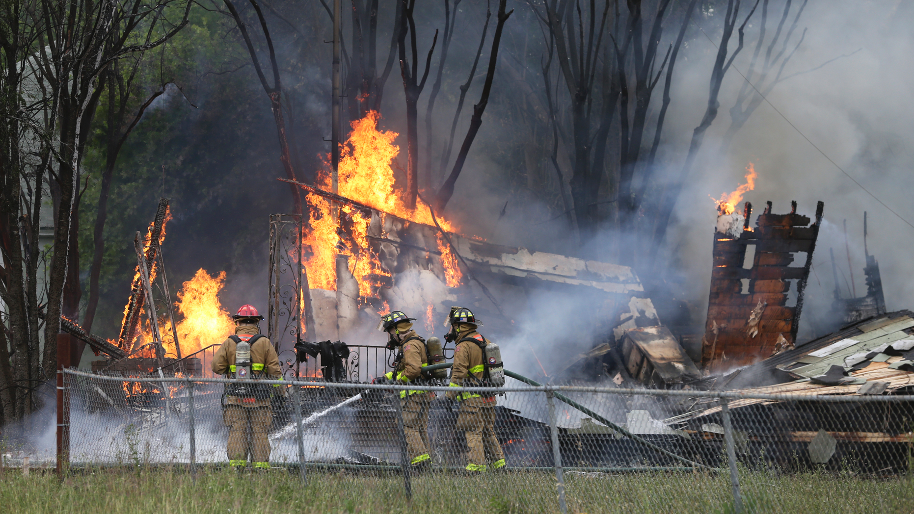 Firefighters work to control a fire at a home in San Antonio, Texas, involving SWAT team members on April 16, 2019. Authorities in San Antonio say a man assaulted his wife, fatally shot a neighbor and set his house on fire before dying in a hail of gunfire with police. Police Chief William McManus says the man "severely" beat his wife Tuesday afternoon and then opened fire on her as she ran away. McManus says the woman wasn't shot but that a neighbor was struck and killed by gunfire. (Tom Reel/The San Antonio Express-News via AP)