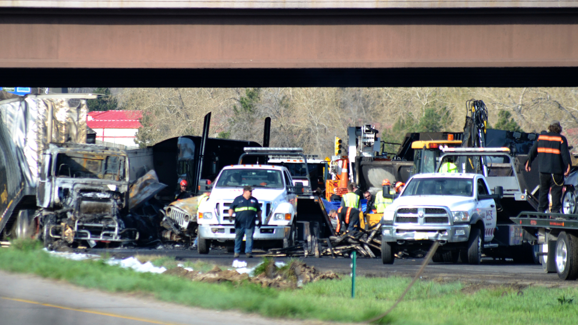 Authorities survey the scene of a fiery crash on I-70 near Colorado Mills Parkway that shut down the highway in both directions on Friday, April 26, 2019. Lakewood, Colo. A truck driver blamed for causing a deadly pileup involving over two dozen vehicles near Denver has been arrested on vehicular homicide charges. Lakewood police spokesman Ty Countryman said Friday that there's no indication that drugs or alcohol played a role in Thursday's crash. (AP Photo/Peter Banda)