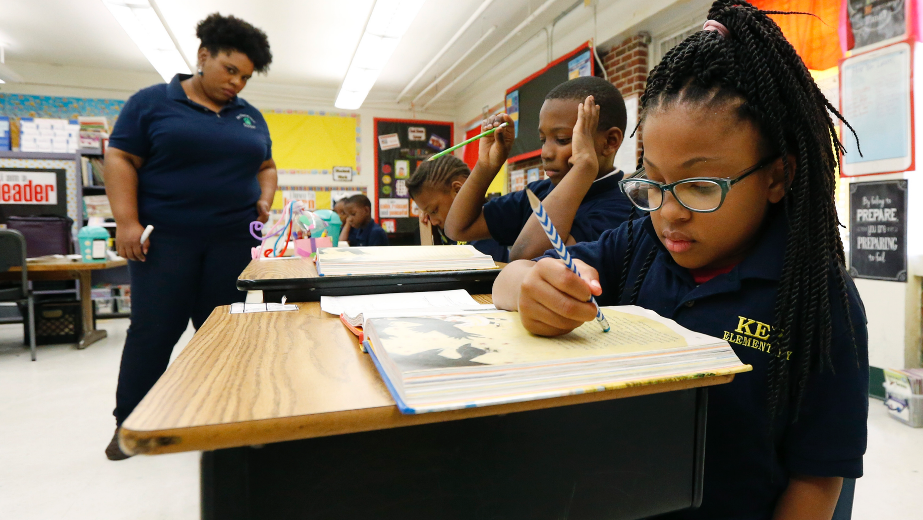Elize's Scott, a third-grade student from Key Elementary School, right, reads under the watchful eyes of teacher Crystal McKinnis, left, on Thursday, April 18, 2019, in Jackson, Missouri, More than 35,000 third-year Mississippi students sat in front of computers this week to take reading tests, facing a state mandate 