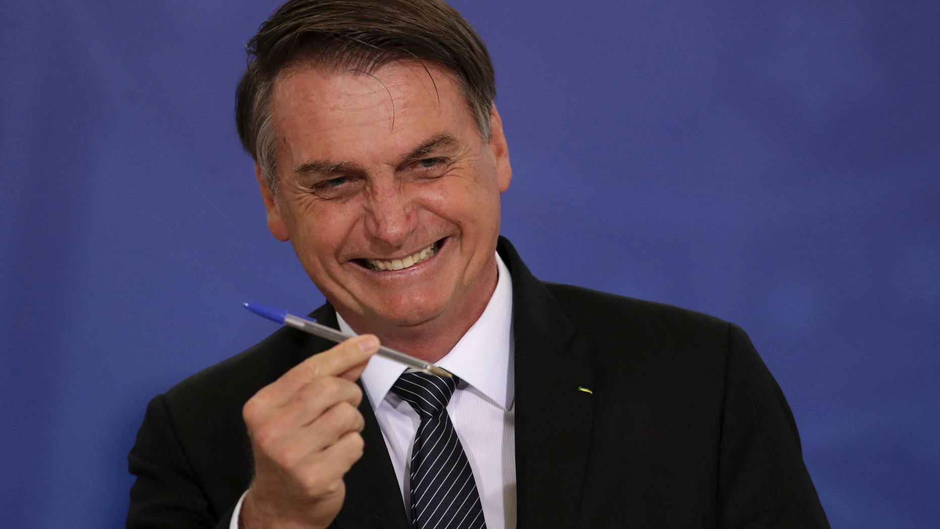 Brazil's President Jair Bolsonaro shows his pen before signing the law that creates credit for small enterprises, during a ceremony at the Planalto Presidential Palace, in Brasilia, Brazil, Wednesday, April 24, 2019. (AP Photo/Eraldo Peres)