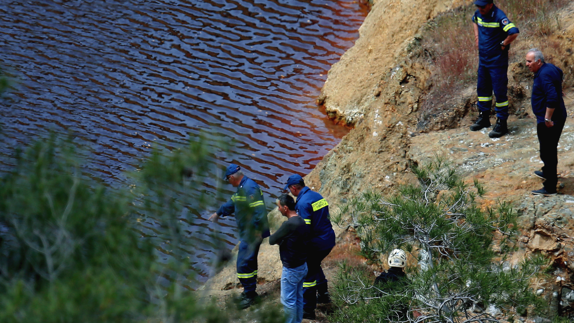 Firefighters and investigators search the man-made lake near the village of Mitsero outside of the capital Nicosia, Cyprus, Friday, April 26, 2019. Cyprus police are intensifying a search for the remains of more victims at locations where an army officer who authorities say admitted to killing five women and two girls had dumped their bodies.