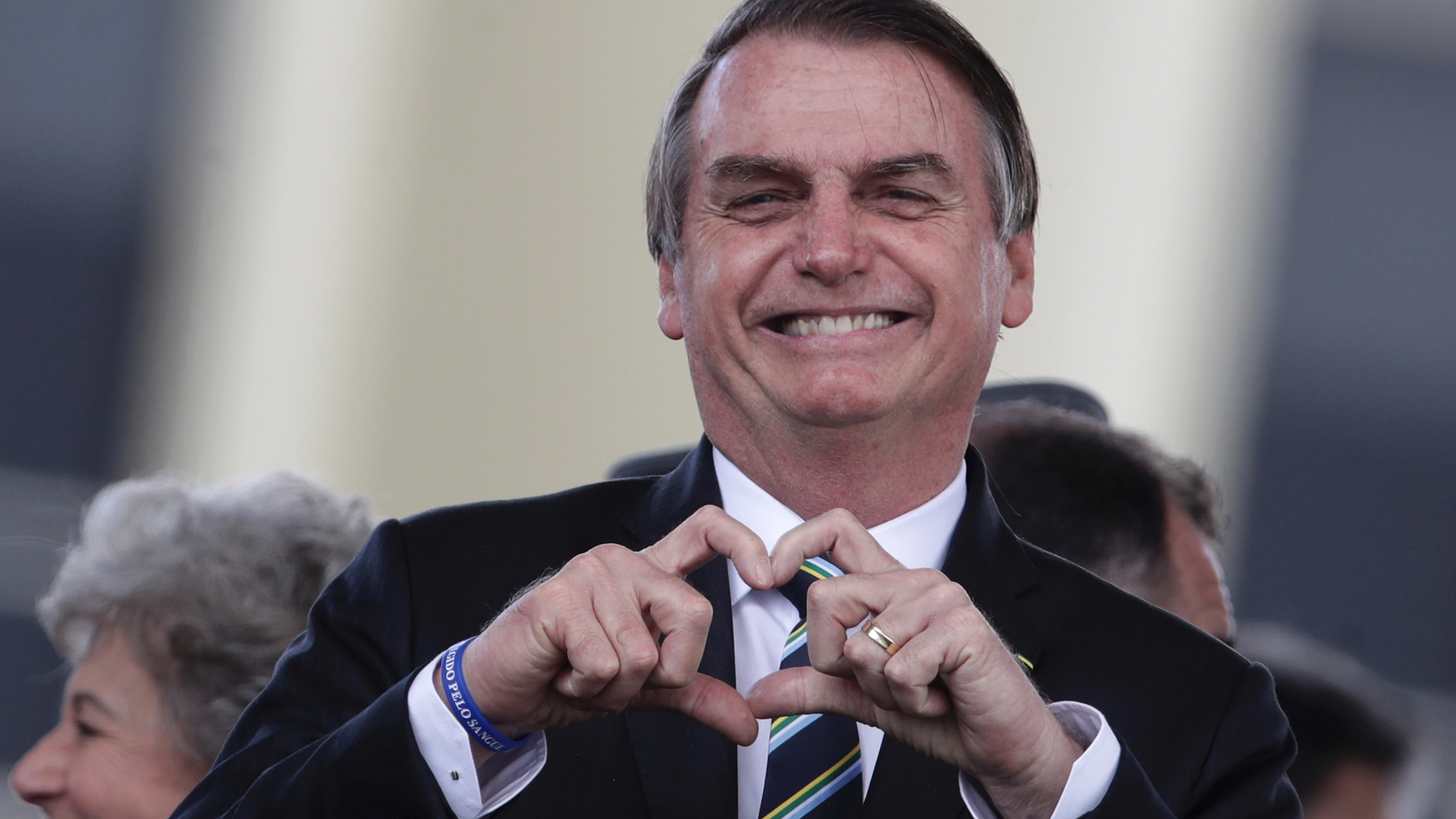 Brazil's President Jair Bolsonaro flashes a heart-hand symbol during a ceremony marking Brazilian Army Day, in Brasilia, Brazil, Wednesday, April 17, 2019. (AP Photo/Eraldo Peres)