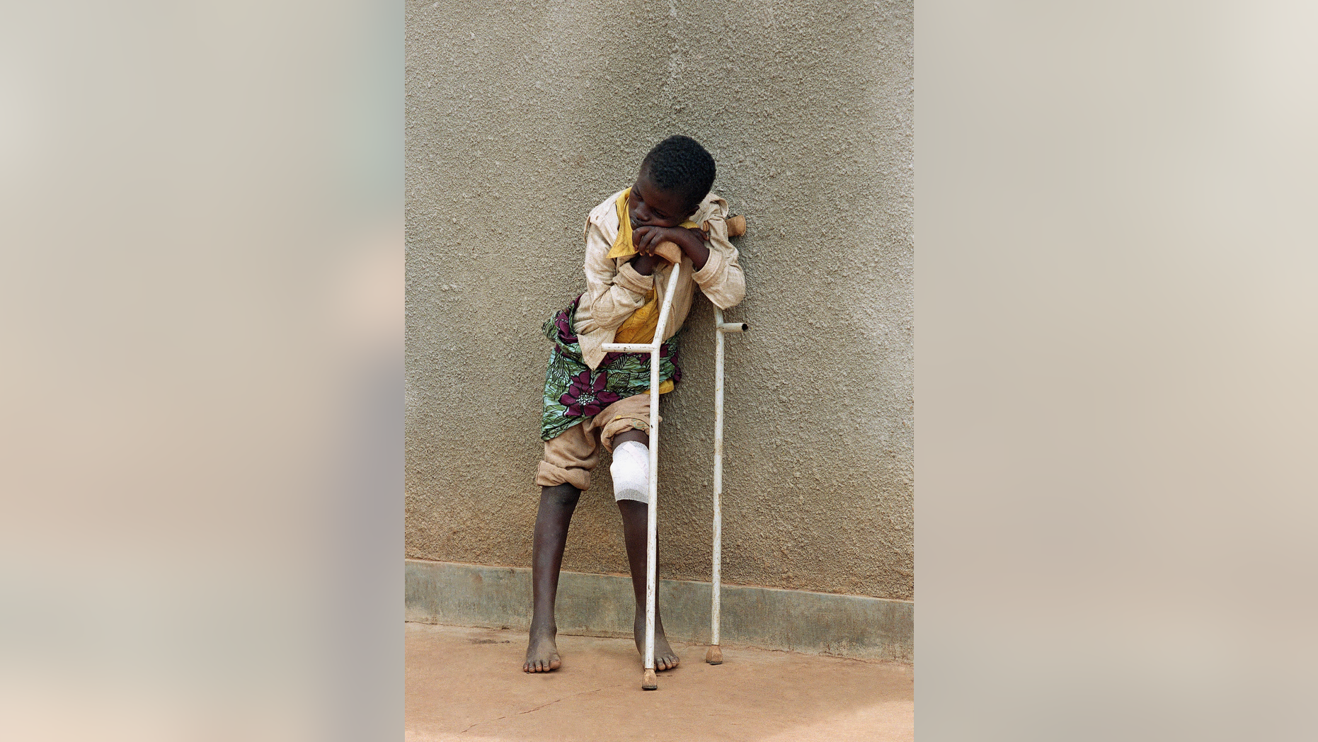 FILE - In this Friday May 13, 1994 file photo a boy who survived a massacre at the Rwandan village of Karubamba rests on his crutches on at a hospital in nearby Gahini, Rwanda. The boy's leg was injured by a machete during the April massacre in Karubamba. Nobody lives here anymore. Not the expectant mothers huddled outside the maternity clinic, not the families squeezed into the church, not the man who lies rotting in a schoolroom beneath a chalkboard map of Africa. (AP Photo/Jean-Marc Bouju, File)