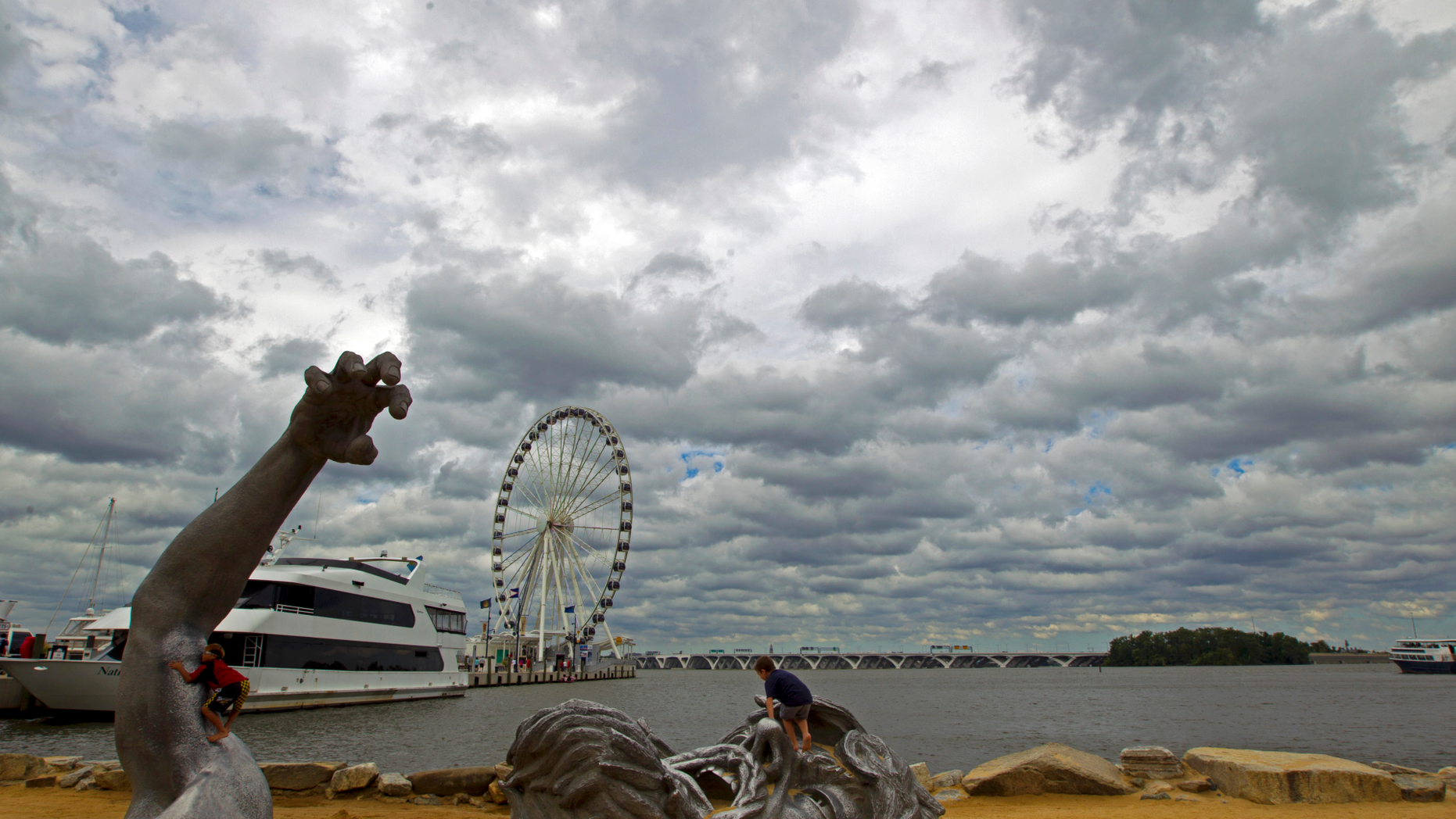 FILE - In this Sept. 3, 2016, file photo, children play on J. Seward Johnson's sculpture, "The Awakening," along the Potomac River waterfront at National Harbor, Md. Federal prosecutors say a man inspired by the Islamic State group stole a U-Haul truck with plans to drive it into a crowd at National Harbor, a convention and tourist destination just outside the nation's capital. (AP Photo/Jose Luis Magana, File)