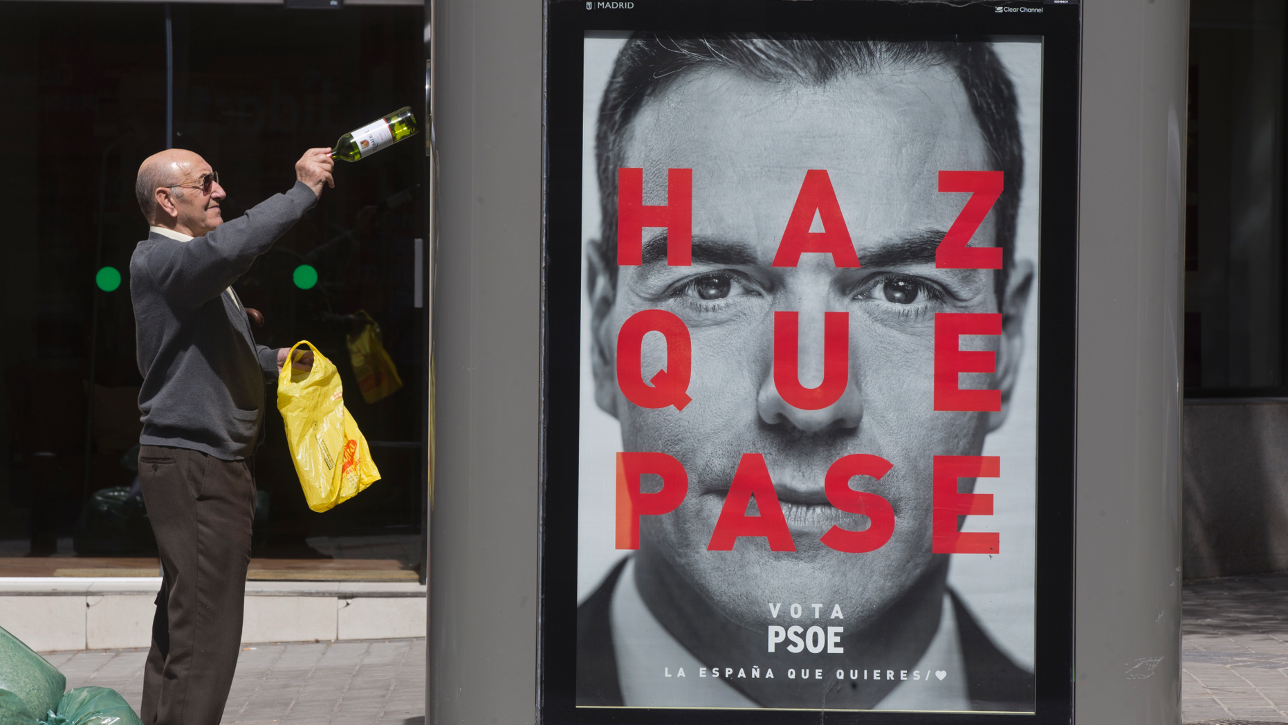 A man disposes of an empty bottle into a recycling container with an election poster showing the face of Socialist prime minister Pedro Sanchez in Madrid, Spain, Tuesday, April 16, 2019. Voters go to the polls for general elections on April 28, when the Socialists will try to remain in power and the extreme right will aim to break into the national Parliament. Message reads 'Make it happen. Vote PSOE, The Spain that you Want'. (AP Photo/Paul White)