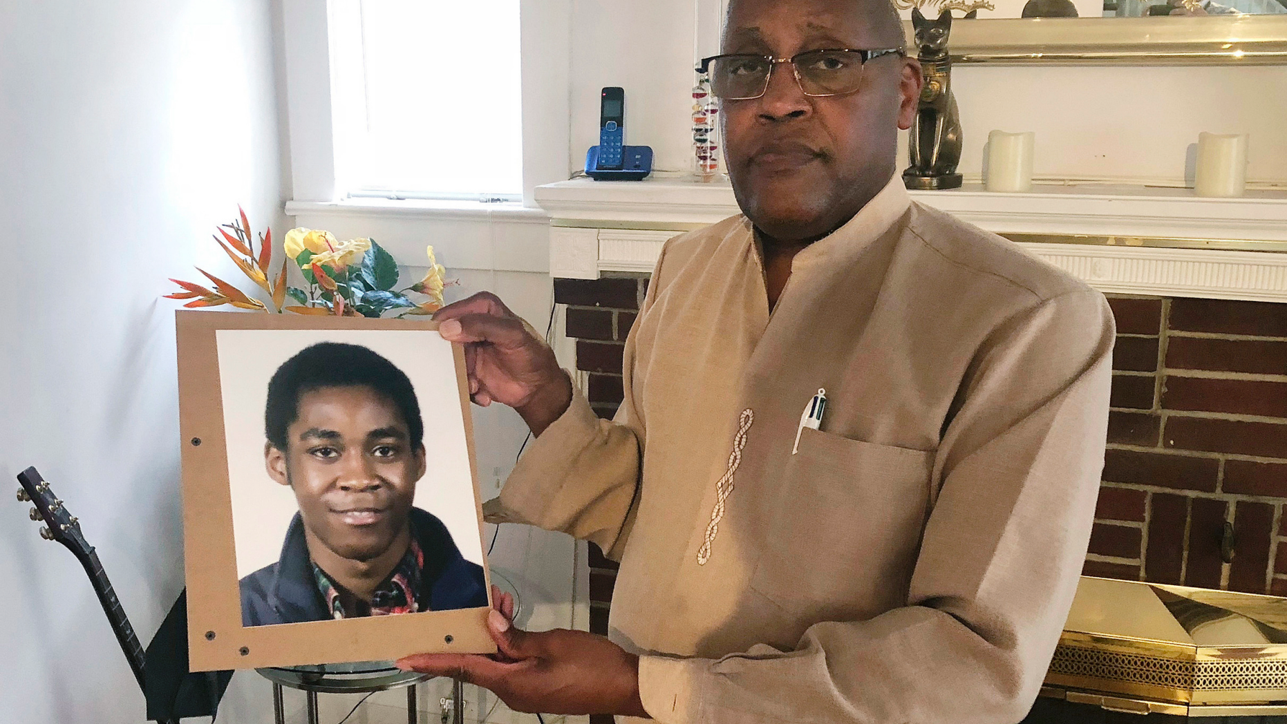 FILE - In this Sept. 5, 2018 file photo, Dia Khafra, father of Askia Khafra, holds a photo of his son in his Silver Springs, Md., home. Jurors are set to hear closing arguments Tuesday, April 23, 2019, in the trial of Daniel Beckwitt, a 27-year-old millionaire. Beckwitt is charged with second-degree murder and involuntary manslaughter in the September 2017 death of 21-year-old Askia Khafra. A fire erupted and killed Khafra, who was helping Beckwitt dig tunnels for an underground nuclear bunker. (AP Photo/Michael Kunzelman, File)