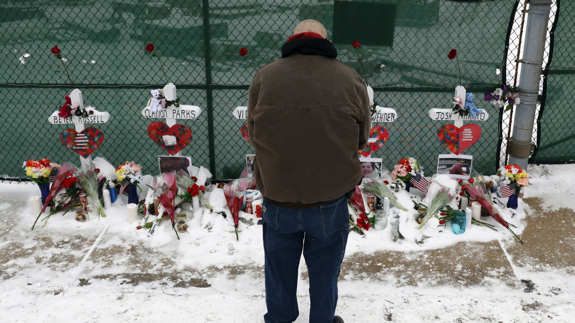 DOSSIER - In this archive photo of February 17, 2019, a man prays at a makeshift memorial placed for five victims near the warehouse of Henry Pratt Co., in Aurora, Illinois. A report on the February shootout in the Chicago manufacturing plant revealed that the man who killed five people after his dismissal told another employee that he was losing his job he would kill other workers and 