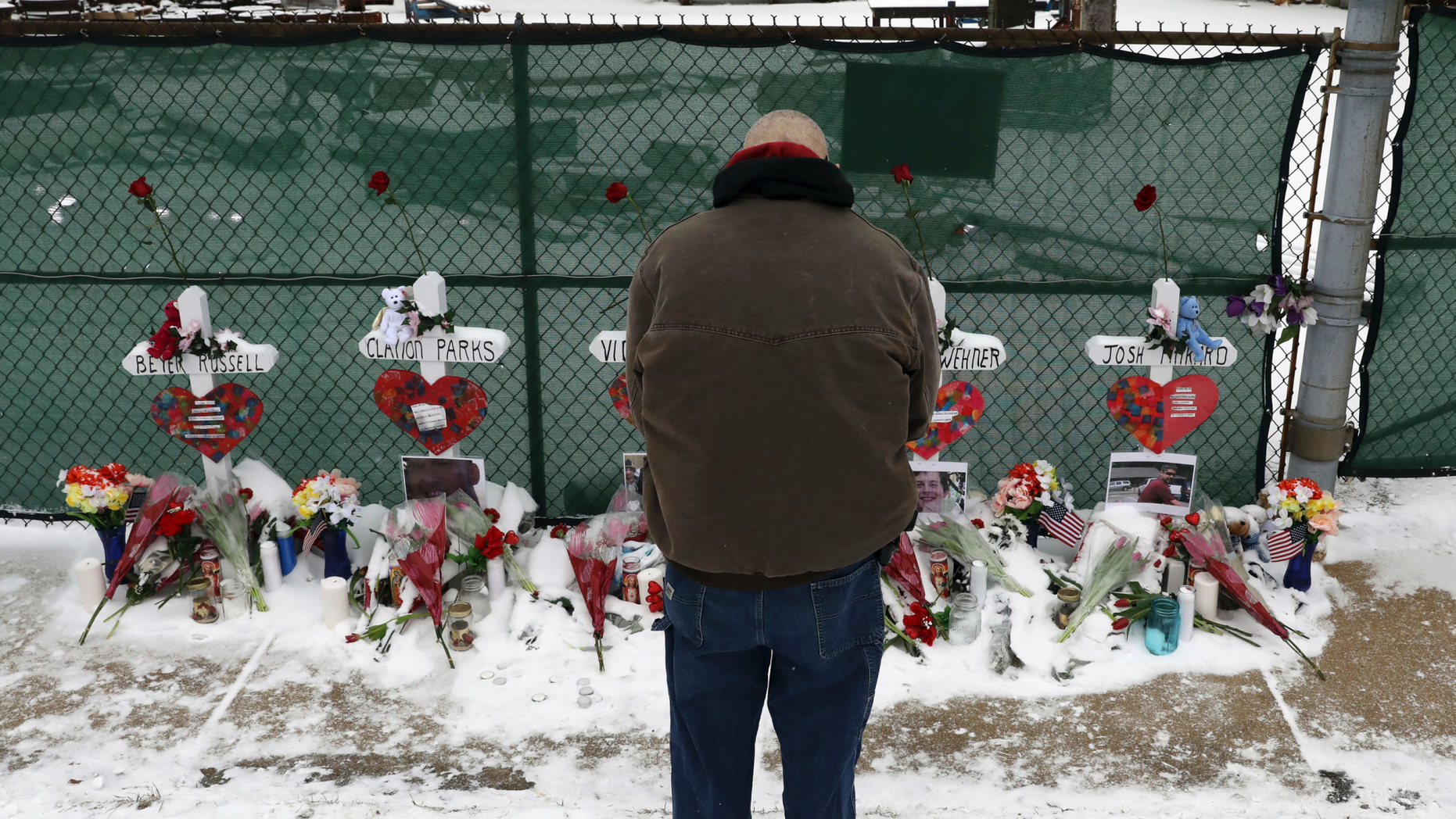 FILE - In this Feb. 17, 2019 file photo a man prays at a makeshift memorial placed for five victims near the warehouse of Henry Pratt Co., in Aurora, Ill. A report on the February shooting at the suburban Chicago manufacturing plant found that the man who killed five people after he was fired told another employee that if he lost his job he would kill other workers and "blow police up." The Kane County State's Attorney's office report released Monday, April 29, 2019, says the other Henry Pratt Co. employee didn't report Gary Martin's comments to superiors because Martin routinely made "off the wall" statements and that he didn't believe Martin would do anything violent. (AP Photo/Nam Y. Huh, File)