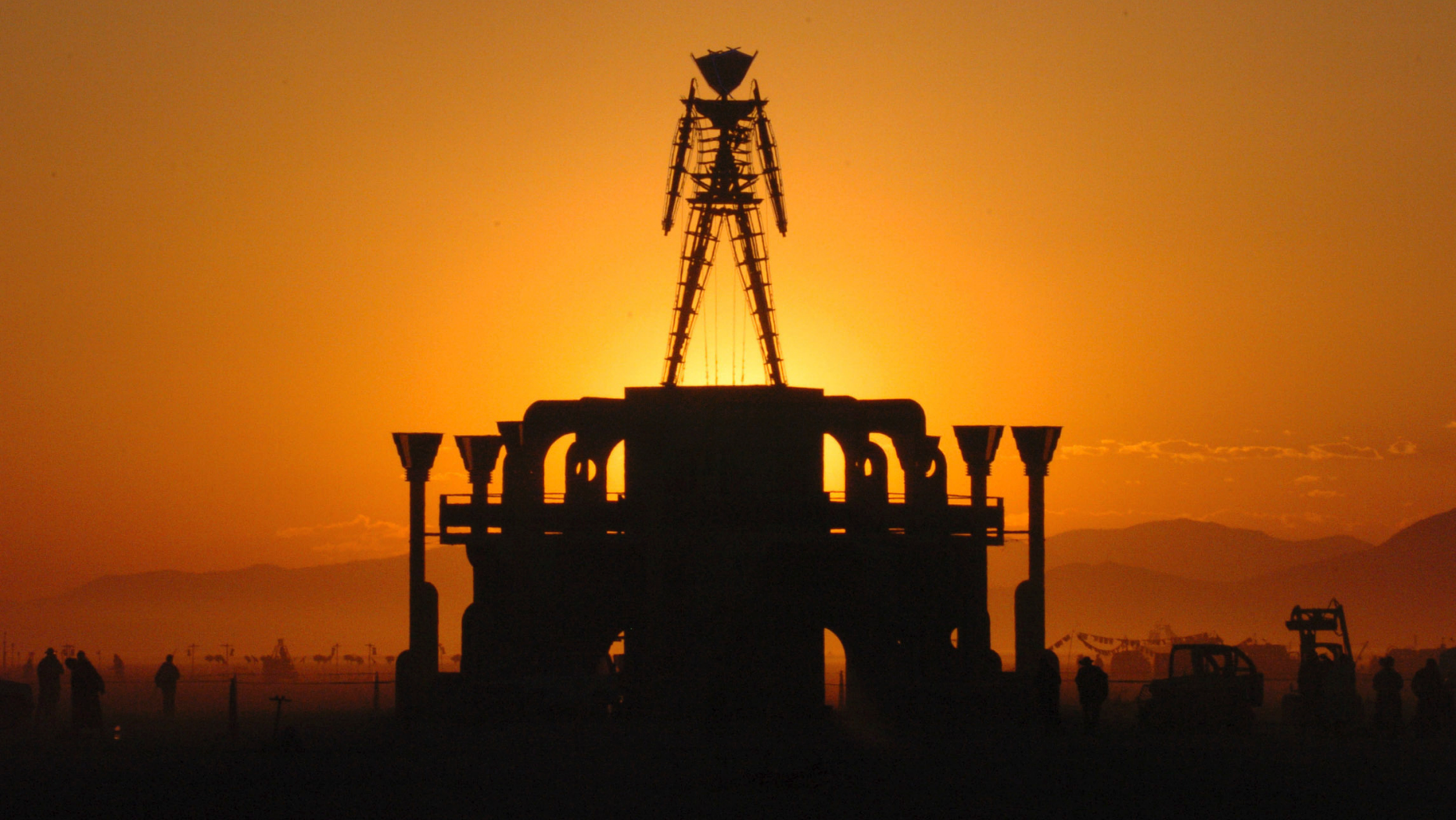 FILE - In this Sept. 2, 2006 file photo, The Man, a stick figured symbol of the Burning Man art festival, is silhouetted against a morning sunrise in Nevada's Black Rock Desert. Burning Man organizers say the U.S. government wants to place unreasonable conditions on a proposal to expand the counter-culture festival's capacity to 100,000, including more security searches and hardened barriers around the perimeter that the agency says would reduce vulnerability to terrorism. (AP Photo/Ron Lewis, File)