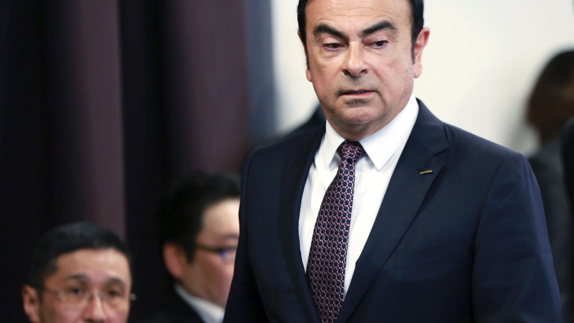 FILE - In this May 12, 2016, file photo, then Nissan Motor Co. President and CEO Carlos Ghosn arrives for a joint press conference with Mitsubishi Motors Corp. in Yokohama, near Tokyo. At left is Nissan Chief Executive Hiroto Saikawa. Nissan Chief Executive Saikawa has apologized to shareholders for the unfolding scandal at the Japanese automaker and asked for their approval to oust from the board former Chairman Ghosn, who has been arrested on financial misconduct charges. Saikawa and other Nissan Motor Co. executives bowed deeply at a Tokyo hotel Monday, April 8, 2019, where the extraordinary shareholders' meeting was being held.(AP Photo/Eugene Hoshiko, File)