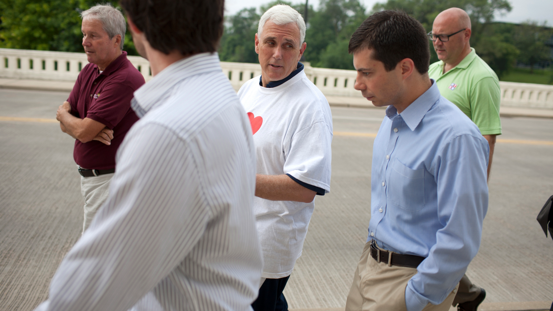 FILE - IN this July 3, 2013, file photo, then-Indiana Gov. Mike Pence, center, talks with South Bend mayor Pete Buttigieg, right, as they cross the Jefferson Boulevard bridge during a fitness walk along the St. Joseph River in downtown South Bend, Ind. Democratic presidential candidate Pete Buttigieg blasts Vice President Mike Pence’s religious conservatism. But as the mayor of South Bend, Indiana, his tone toward the state’s former governor was more muted. The two once had a cordial relationship. (AP Photo/South Bend Tribune, James Brosher)/South Bend Tribune via AP)