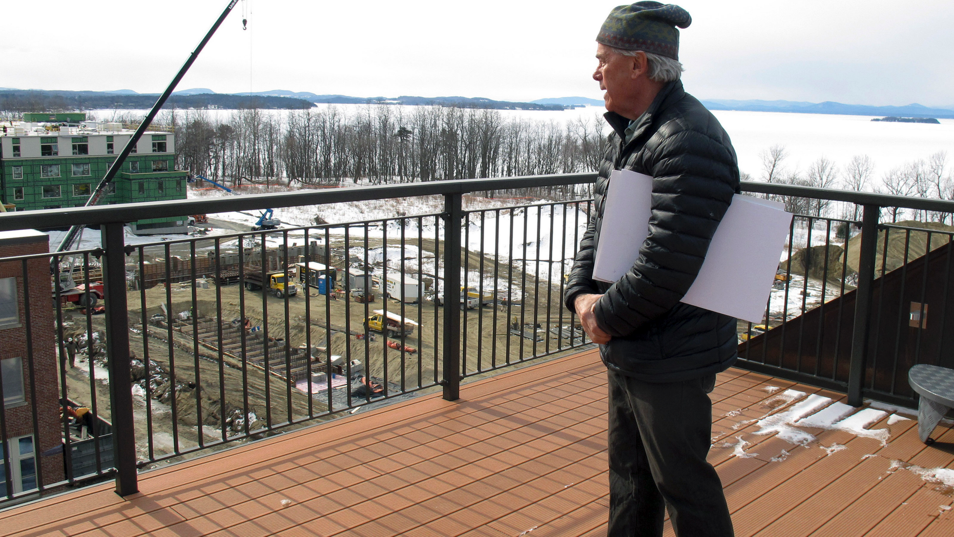In this March 7, 2019 photo, developer Eric Farrell looks at construction on the property that once housed Burlington College, and before that was an orphanage run by the Roman Catholic Diocese, on the shore of ice-covered Lake Champlain, background, in Burlington, Vt. The property is being redeveloped and city officials say it will be a boost to the entire community. (AP Photo/Wilson Ring)