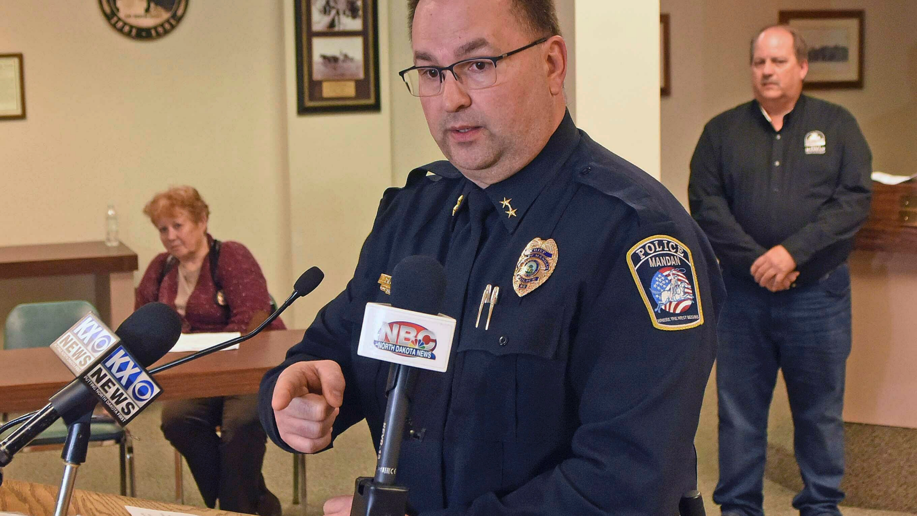 Mandan Police Chief Jason Ziegler announces an arrest in a quadruple homicide at a press conference Thursday night, April 4, 2019, in Mandan, N.D. In back are Deputy Police Chief Lori Flaten, left, and Mandan Mayor Tim Helbling. Police in North Dakota say they've arrested a 44-year-old man in the slayings of four people earlier this week at a business in Mandan. Ziegler says surveillance video identified a vehicle of interest and helped lead them to the suspect, who lived in the small town of Washburn about 35 miles (56 kilometers) north of Mandan. (Tom Stromme/The Bismarck Tribune via AP)