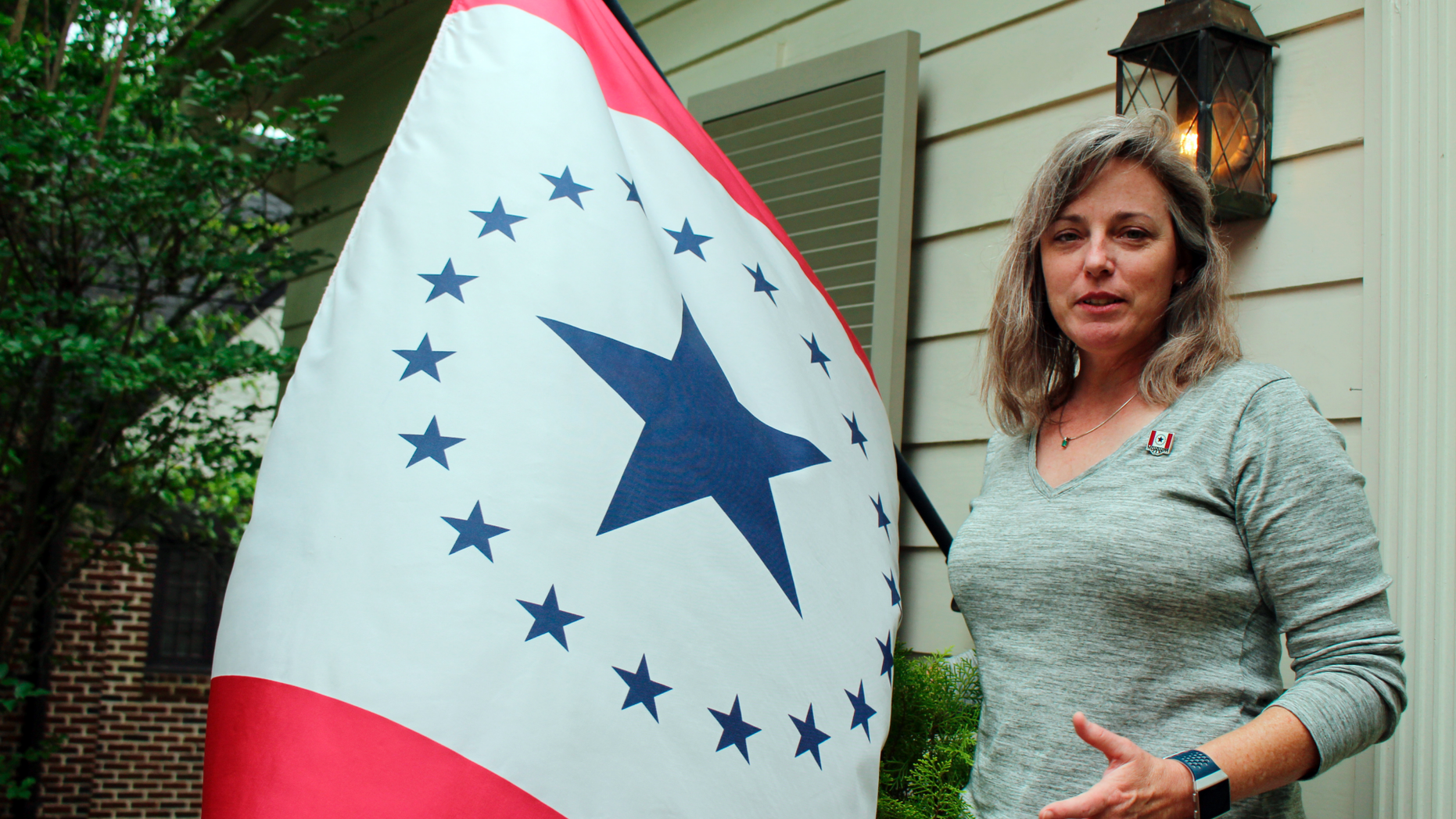 Laurin Stennis, an artist, speaks outside her home in Jackson, Miss., on Wednesday, April 17, 2019, and explains how she thinks a flag she designed, which flies next to her, would be an appropriate symbol to replace the state flag that Mississippi has used since 1894. The current flag includes the Confederate battle emblem, and Stennis's design does not. Mississippi Gov. Phil Bryant has signed a bill that authorizes several new specialty license plates, including one featuring the "Stennis flag." (AP Photo/Emily Wagster Pettus)