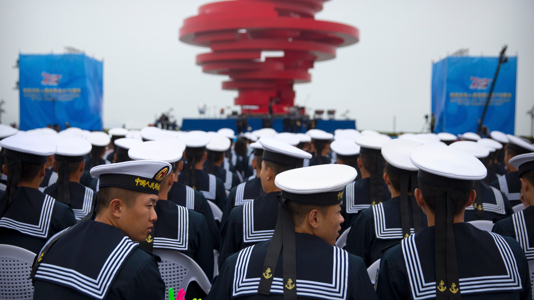 Chinese sailors sit during a concert featuring Chinese and foreign military bands in Qingdao, Monday, April 22, 2019. Ships from Chinese and foreign navies have gathered in Qingdao for events this week, including a naval parade, to mark the 70th anniversary of the founding of the People's Liberation Army (PLA) Navy. (AP Photo/Mark Schiefelbein)