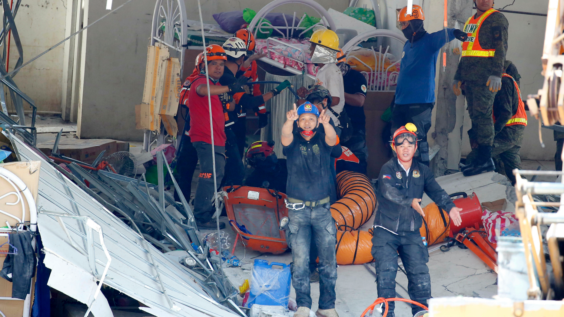 Rescuers gesture to clear the way following the discovery of another survivor in Monday's magnitude 6.1 earthquake that caused the collapse of a commercial building in Porac township, Pampanga province north of Manila, Philippines Tuesday, April 23, 2019. A strong earthquake struck the northern Philippines Monday trapping some people in a collapsed building, damaged an airport terminal and knocked out power in at least one province, officials said. (AP Photo/Bullit Marquez)