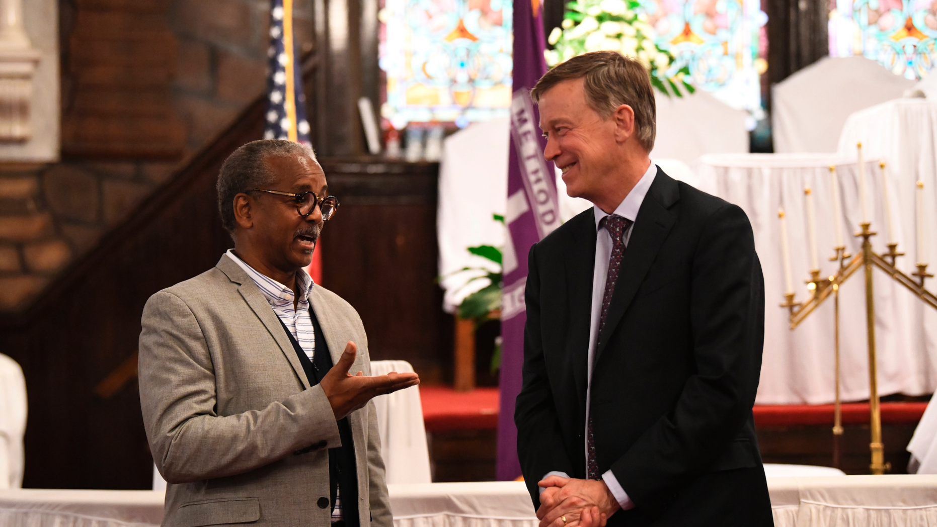 Former Colorado Gov. John Hickenlooper discusses gun control and death penalty issues with Anthony Thompson on Saturday, April 6, 2019, in Charleston, S.C. Thompson's wife was slain in a massacre that claimed nine Bible study participants at a historic black church in South Carolina. Hickenlooper, a staunch advocate for gun control legislation, visited Mother Emanuel during a campaign trip to the state as he seems the Democratic presidential nomination. (AP Photo/Meg Kinnard)