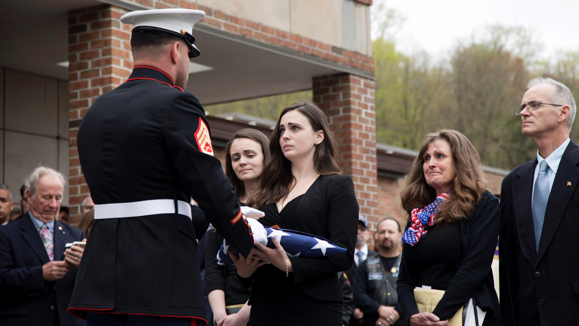 Beth Regan is presented with the flag that draped the casket of her friend Marine Private First Class Robert Graham on Friday, April 26, 2019 in Shrub Oak, NY. Graham, who died at 97 has no living family members but Regan arranged for hundreds to attend his funeral. "Receiving the flag was like receiving a part of him," Regan said. (AP Photo/Allyse Pulliam)