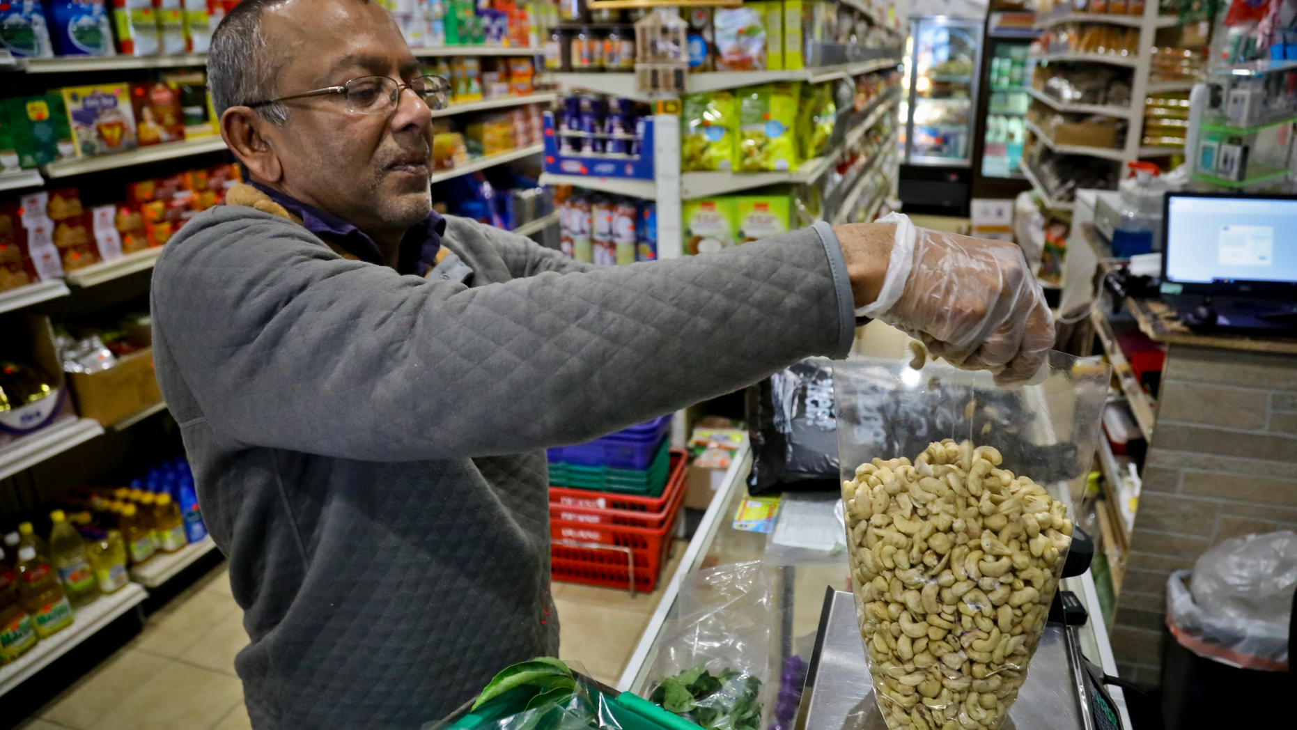 Dhannitha Meemanage, from Sri Lanka, bags cashews in his family's grocery store, in New York's Staten Island's "Little Sri Lanka" community, Monday, April 22, 2019. Sri Lanka’s abrupt shutdown of social media sites in the wake of the string of deadly Easter Sunday terror attacks has left worried friends and relatives in places like “Little Sri Lanka” in the dark. Meemanage, turned to old-fashioned means of getting news about loved ones after the attack, a landline phone. (AP Photo/Bebeto Matthews)