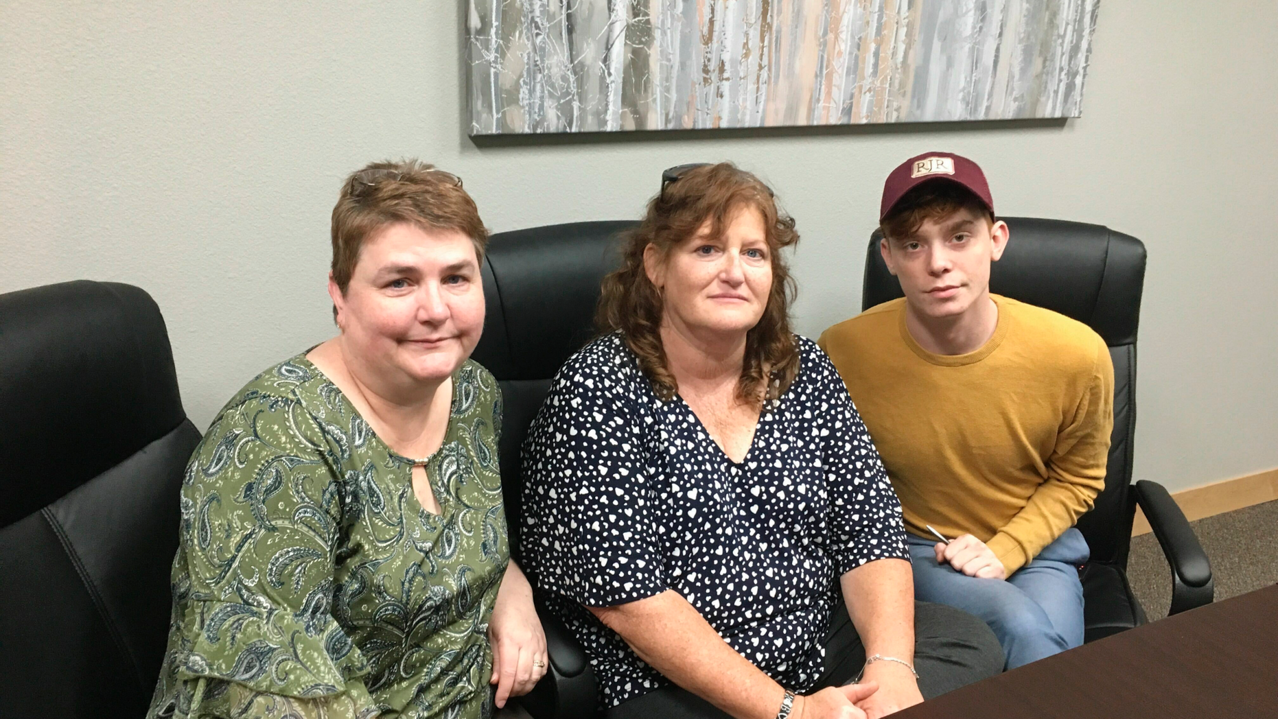 In this Sunday, April 14, 2019, photo, RJR Maintenance and Management office manager Deanna Finnie, left, co-owner Jackie Fakler, center, and marketing executive Ben Pace pose for a photograph at the business in Mandan, N.D., where four people were brutally slain on April 1. Chiropractor Chad Isaak, who lived on property managed by the company, is charged with felony murder in the deaths of co-owner Robert Fakler, Jackie's husband, and three workers. (AP Photo/Blake Nicholson)