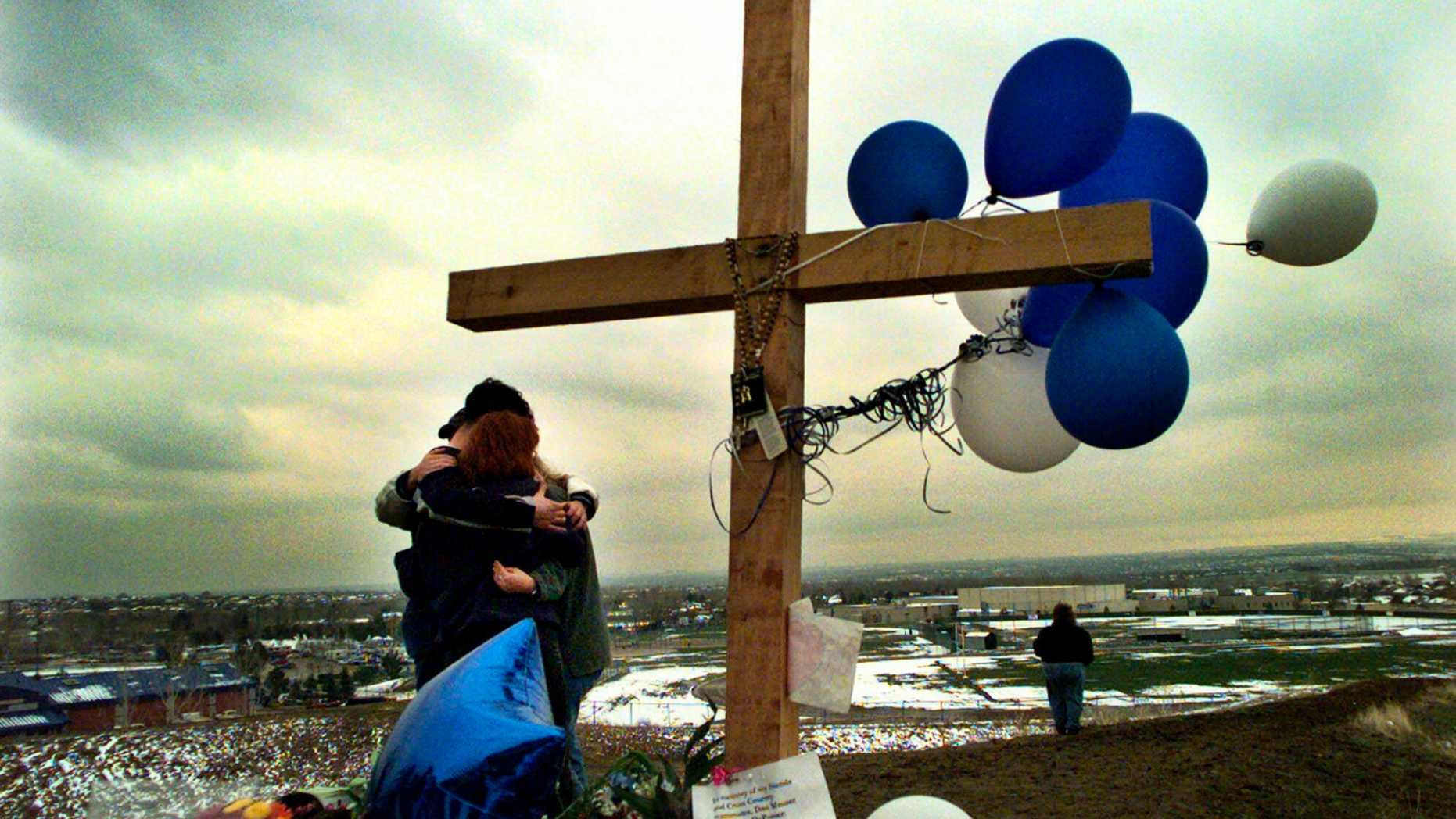 FILE - In this April 24, 1999, file photo, students embrace each other at a makeshift memorial for their slain classmates at Columbine High School on a hilltop overlooking the school in Littleton, Colo. Twelve students and one teacher were killed in a murderous rampage at the school on April 20, 1999, by two students who killed themselves in the aftermath. (AP Photo/Bebeto Matthews, File)