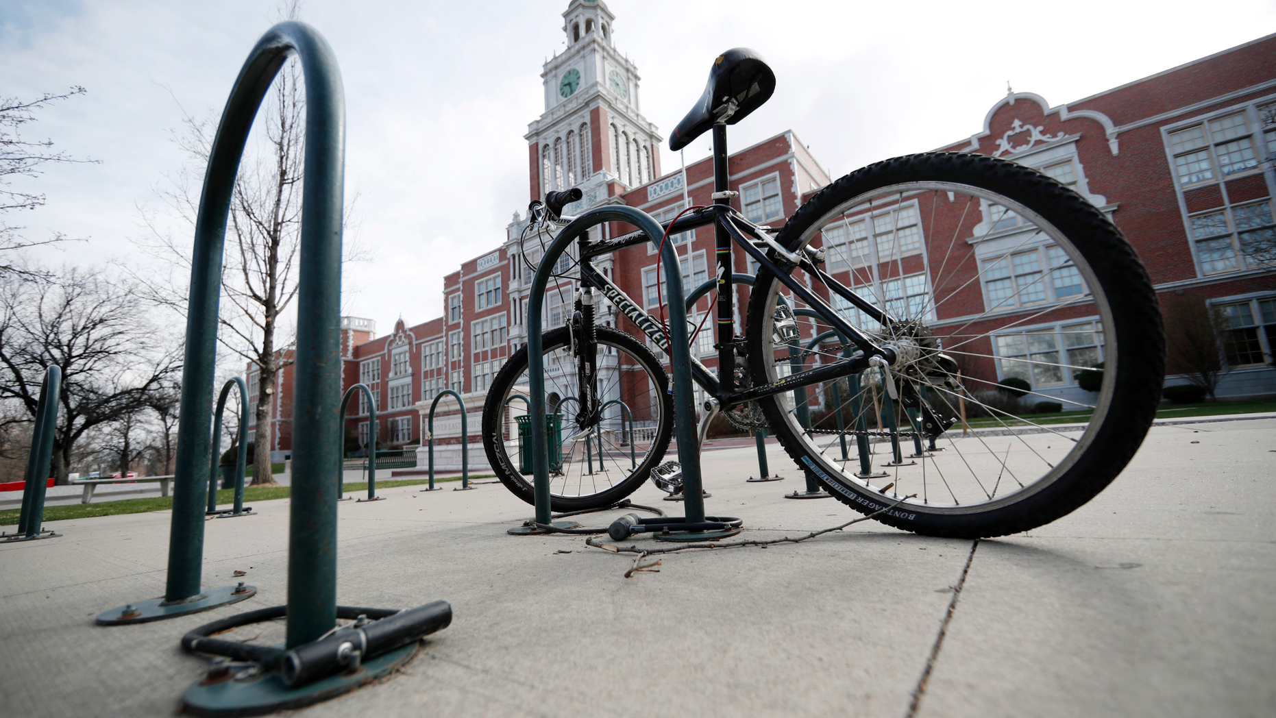 A lone bicycle stands in the rack outside East High School, Wednesday, April 17, 2019, in Denver. Denver-area public schools closed Wednesday as the FBI hunted for an armed young Florida woman who was allegedly "infatuated" with Columbine and threatened violence just days ahead of the 20th anniversary of the attack. (AP Photo/David Zalubowski)