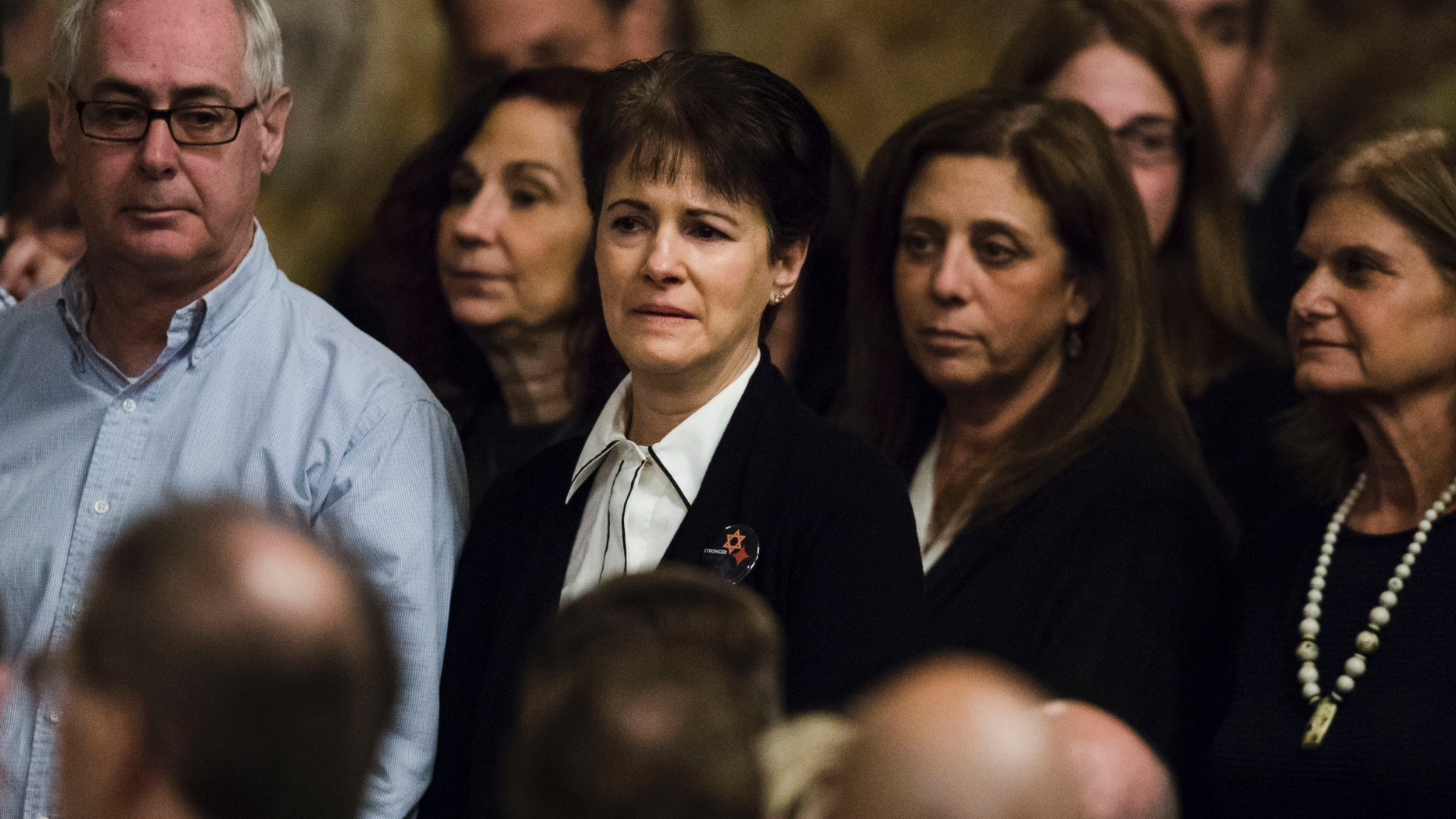 Andrea Wedner, center, who was wounded at the Pittsburgh synagogue attack that killed 11 people last year, stands with others as they are acknowledged by Pennsylvania lawmakers who came together in an unusual joint session to commemorate the victims of synagogue attack, Wednesday, April 10, 2019, at the state Capitol in Harrisburg, Pa. (AP Photo/Matt Rourke)