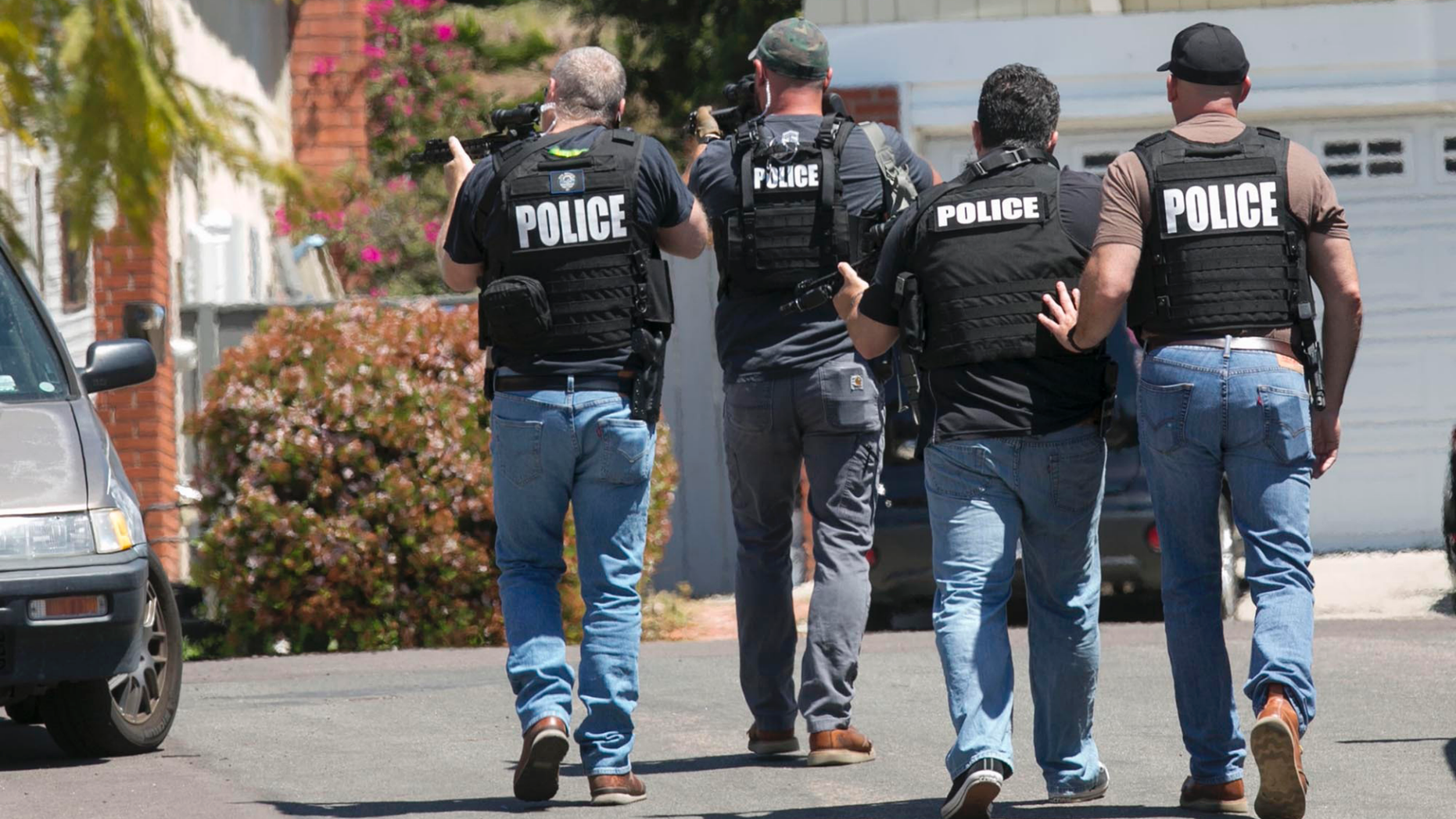 Heavily armed San Diego police officers approach a house thought to be the home of 19 year-old John T. Earnest, who is a suspect in the shooting of several people in a Poway synagogue, on Saturday, April 27, 2019, in San Diego, Calif. A gunman used an AR-type assault weapon to shoot worshippers at Chabad of Poway, San Diego County Sheriff William Gore said. (John Gibbins/The San Diego Union-Tribune via AP)