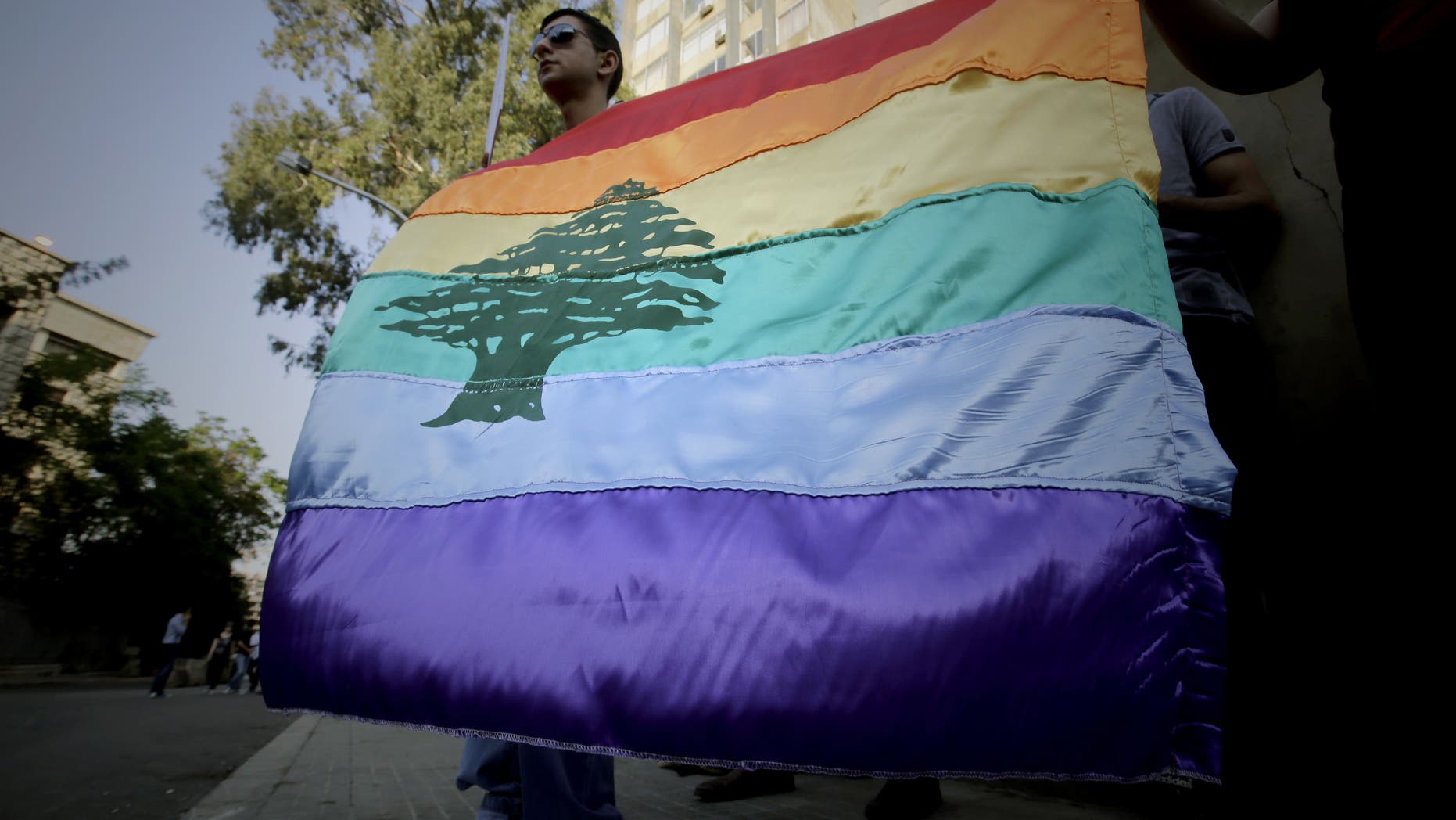 A gay pride flag bearing the cedar tree in the middle of it is carried by human rights activists during an anti-homophobia rally in Beirut on April 30, 2013. Top Lebanese military prosecutors acquitted four military personnel Saturday in a landmark ruling that affirms homosexuality is not a crime.