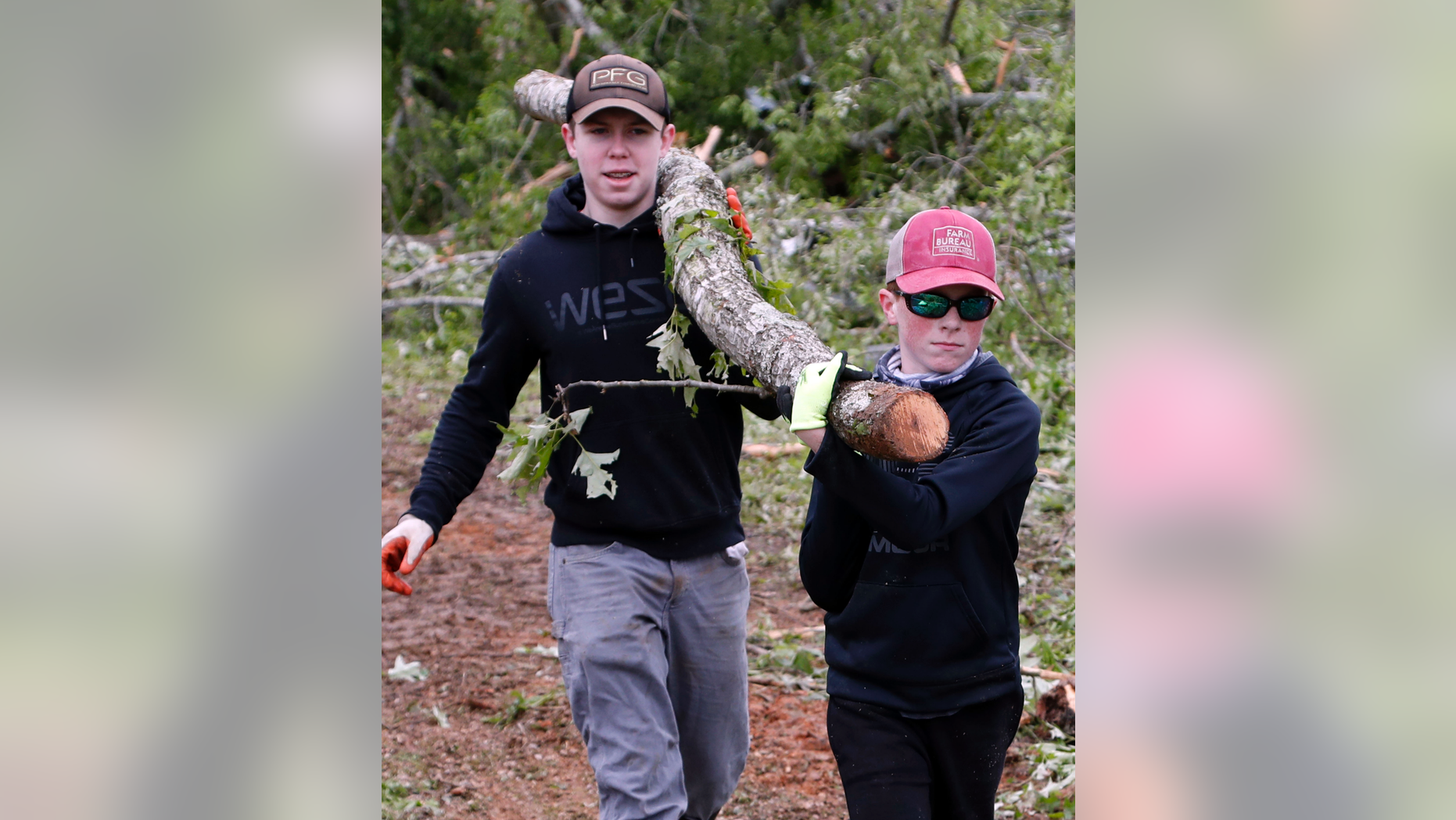 Justus Harvey, 16, left, and his friend Gage Lee, 13, both of Forest, Miss., work in tandem to remove a branch Friday, April 19, 2019, in Morton, Miss., as residents begin their cleanup from Thursday's possible tornado touchdown that heavily damaged many homes. Strong storms again roared across the South on Thursday, topping trees and leaving a variety of damage in Mississippi, Louisiana and Texas. (AP Photo/Rogelio V. Solis)