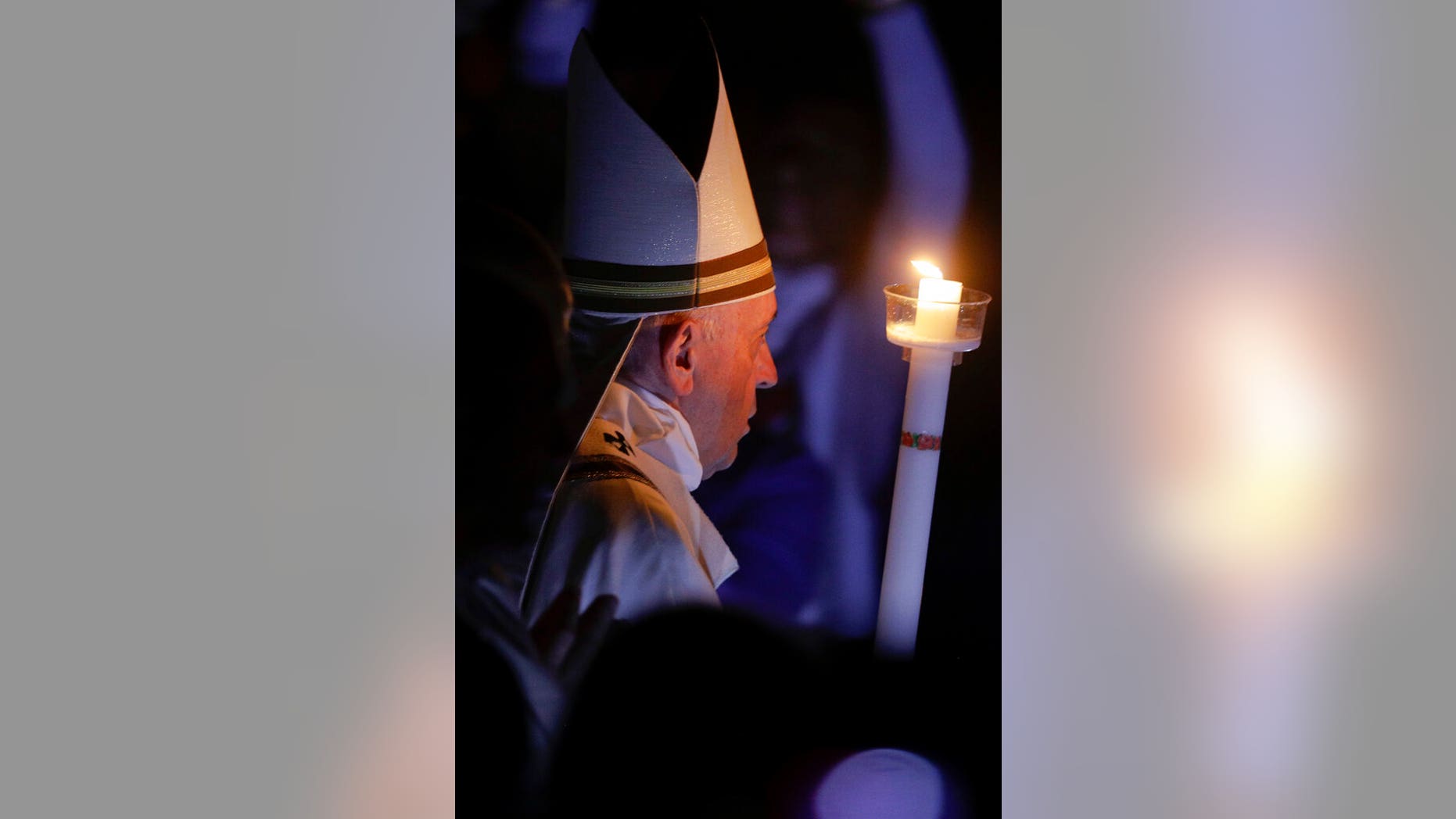 Pope Francis holds a candle as he presides over a solemn Easter vigil ceremony in St. Peter's Basilica at the Vatican, Saturday, April 21, 2019. (AP Photo/Gregorio Borgia)