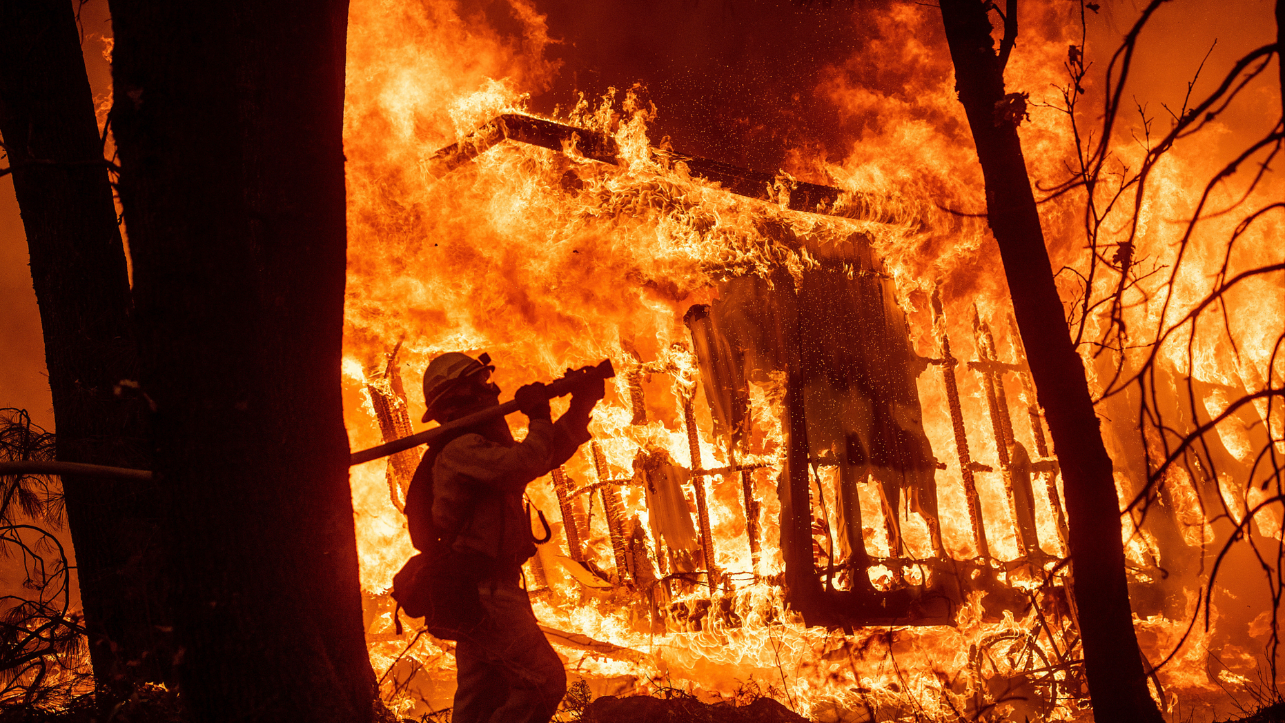 FILE - In this Friday, Nov. 9, 2018 file photo, firefighter Jose Corona sprays water as flames from the Camp Fire consume a home in Magalia, Calif. More than 2.7 million Californians live in areas that are at very high risk for wildfires. One in 12 homes in California are at high risk of burning in a wildfire. The more information we can share about where and how we're falling short, the quicker we can come together on potential solutions. (AP Photo/Noah Berger, File)