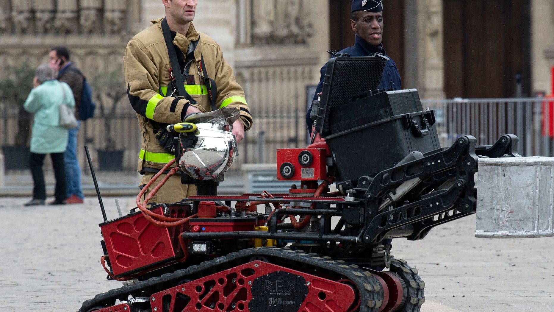 Firefighters are seen with a robot firefighter called Colossus, made by French robotics company Shark Robotics, outside Notre-Dame Cathedral after a major fire yesterday in Paris, France.