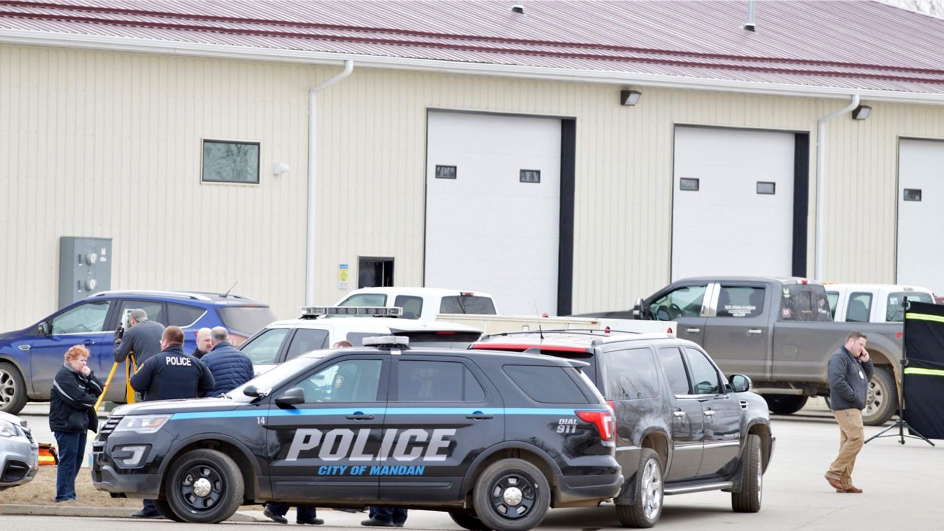 Law enforcement officers stand outside RJR Maintenance and Management in Mandan, North Dakota on Monday, where four people were found dead.