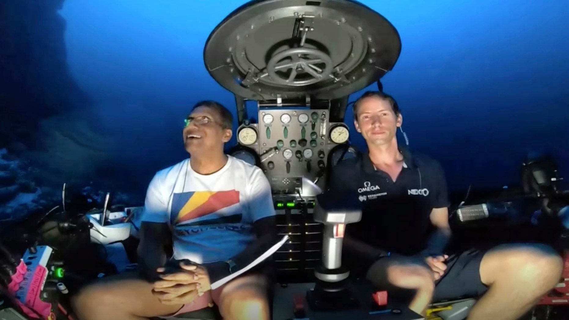 An image taken from video issued by Nekton shows Seychelles President Danny Faure, left, smiles after speaking from inside a submersible from the vessel Ocean Zephyr, under the water off the coast of Desroches, in the outer islands of Seychelles Sunday, April 14, 2019. (Nekton via AP)