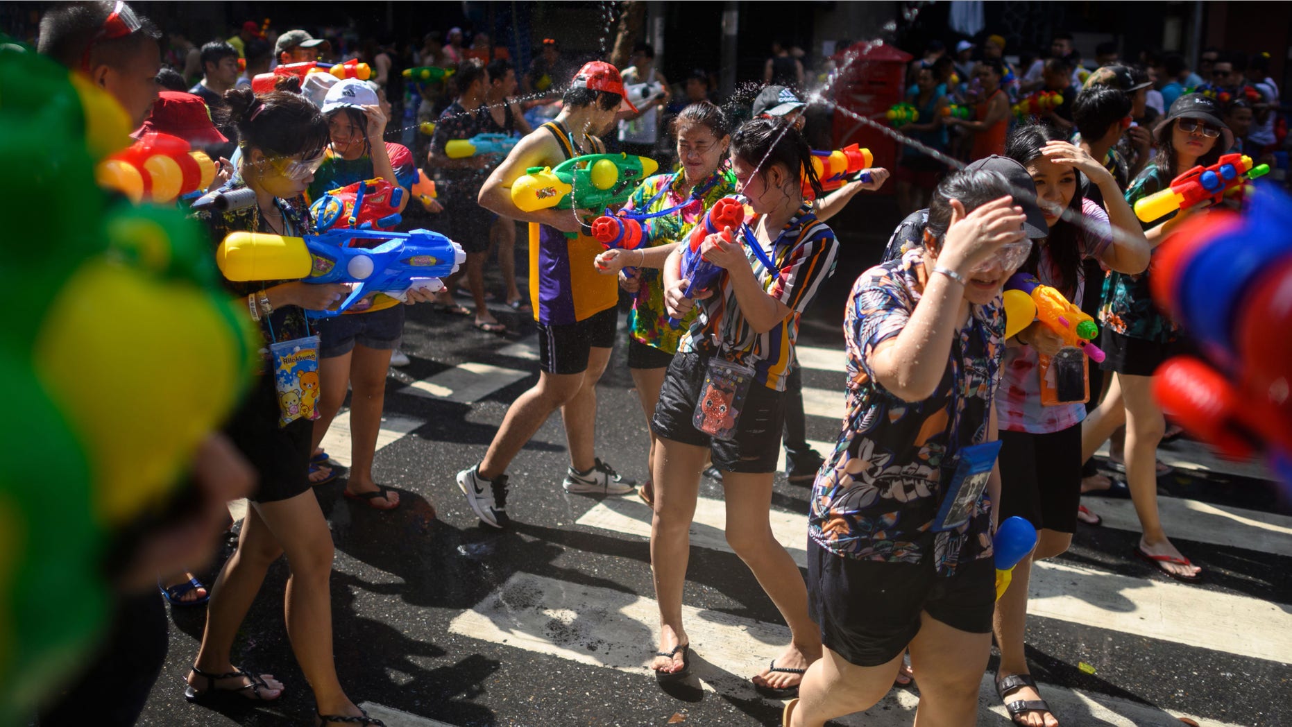 People use water guns to spray at one another as they celebrate the Buddhist New Year, locally known as Songkran, in Bangkok on April 14, 2019.